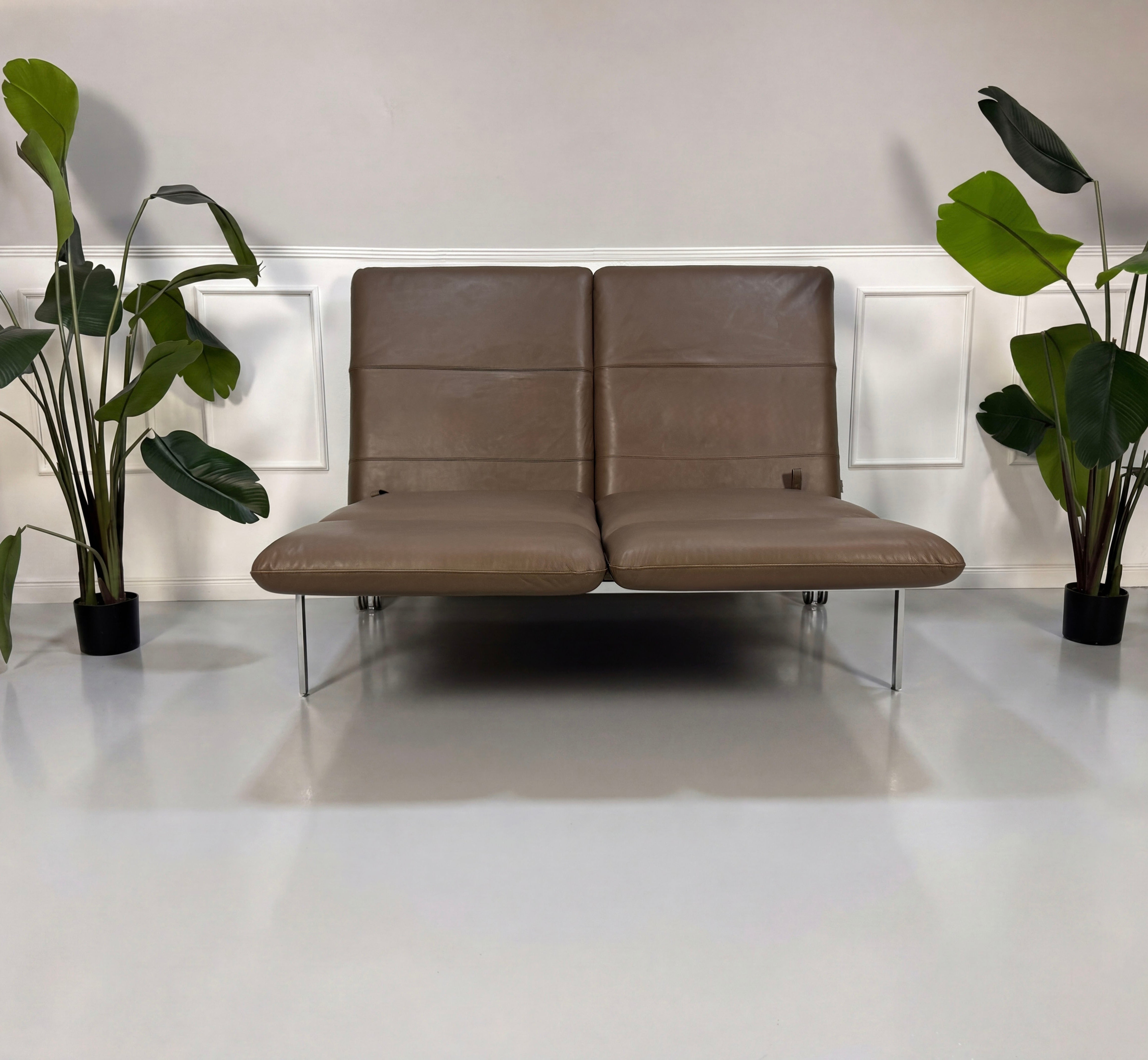 Gebrauchtes braunes Brühl Roro Designer Leder Sofa vor einer Wand, stilvoll und modern eingerichtet.