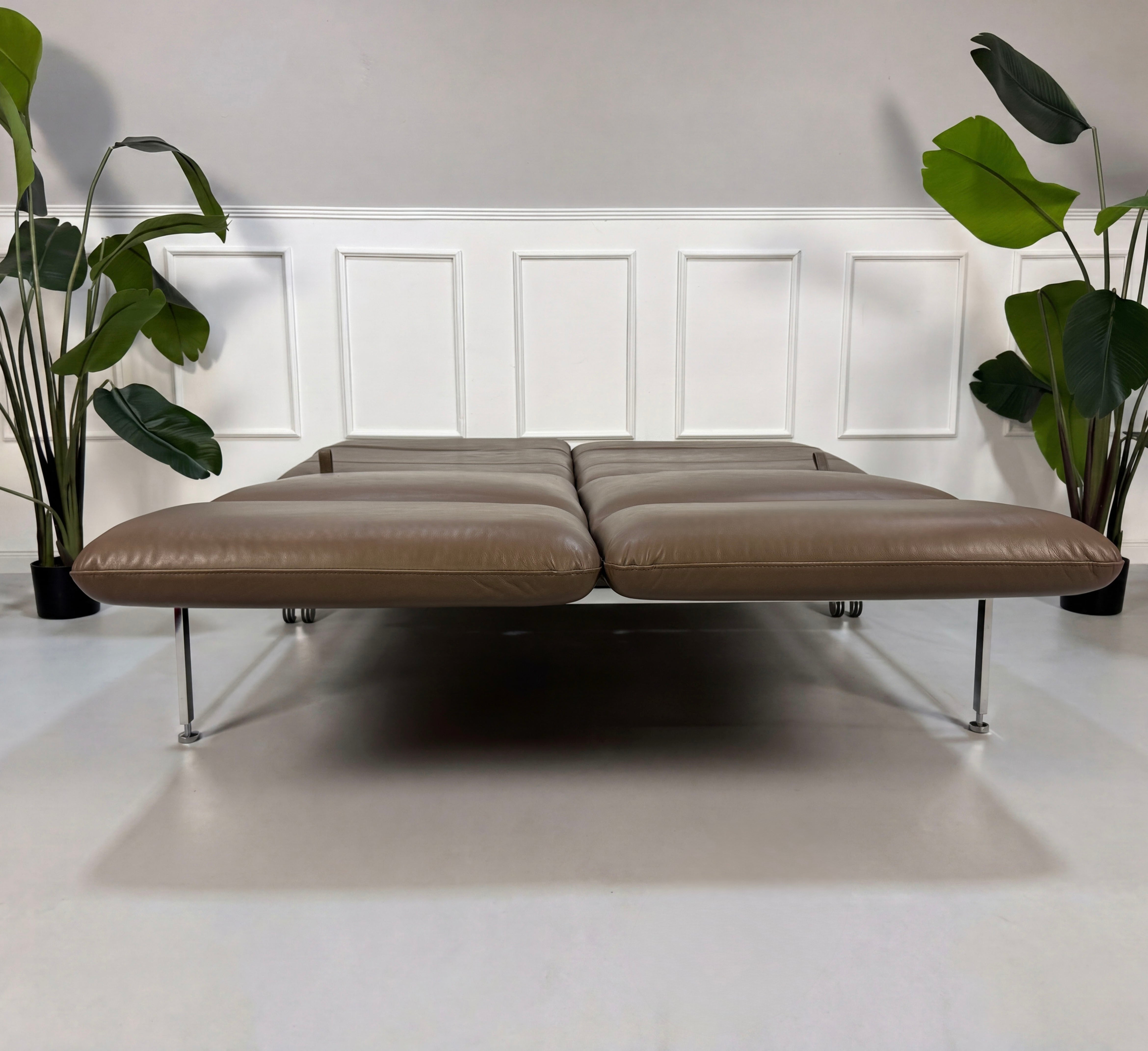 Gebrauchtes braunes Brühl Roro Designer Leder Sofa vor einer Wand, stilvoll und modern eingerichtet.