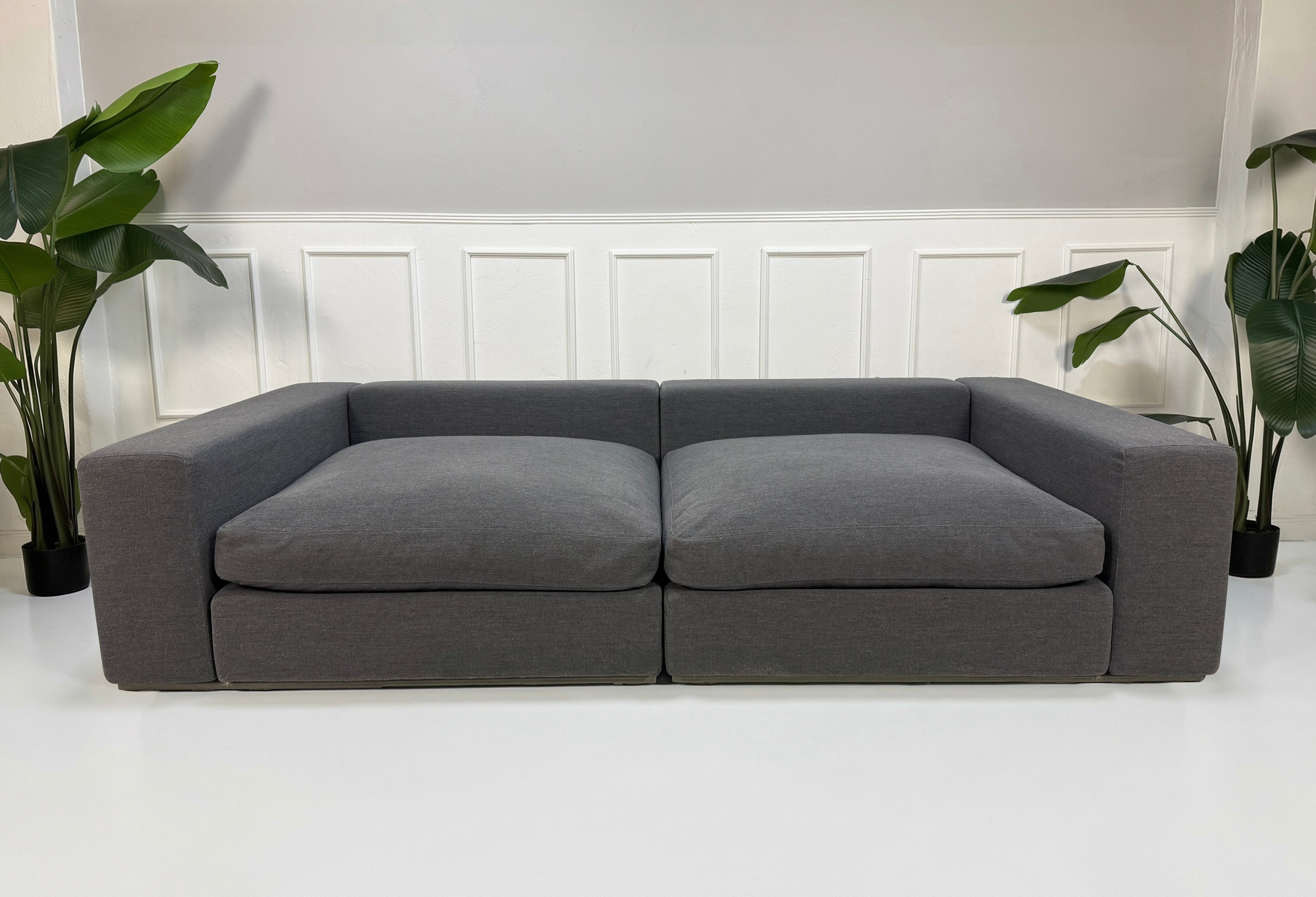 Refurbished graues Flexform Groundpiece Designer Stoff Sofa vor einer Wand, stilvoll und modern eingerichtet.