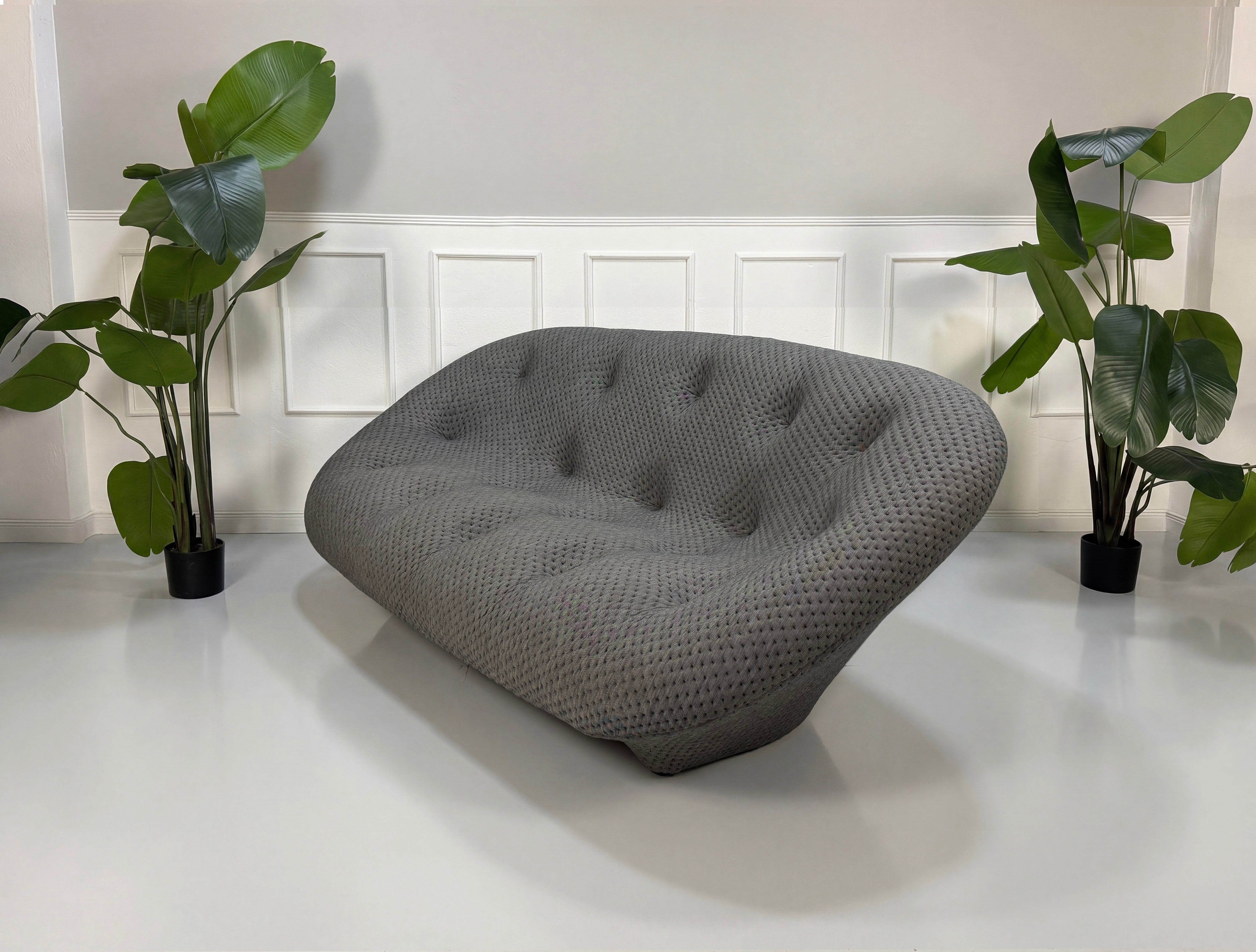 Refurbished graues Ligne Roset Ploum Designer Stoff Sofa vor einer Wand, stilvoll und modern eingerichtet.