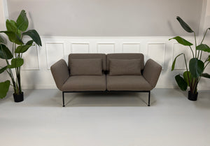 Ausstellungsstück Brühl Roro in braun Designer Stoff Sofa vor einer Wand, stilvoll und modern eingerichtet.