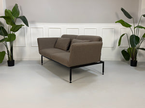 Ausstellungsstück Brühl Roro in braun Designer Stoff Sofa vor einer Wand, stilvoll und modern eingerichtet.