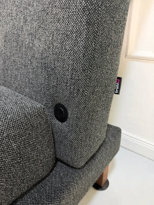 Gebrauchter Brühl Moule Designer Stoff Sessel vor einer Wand, stilvoll und modern eingerichtet.