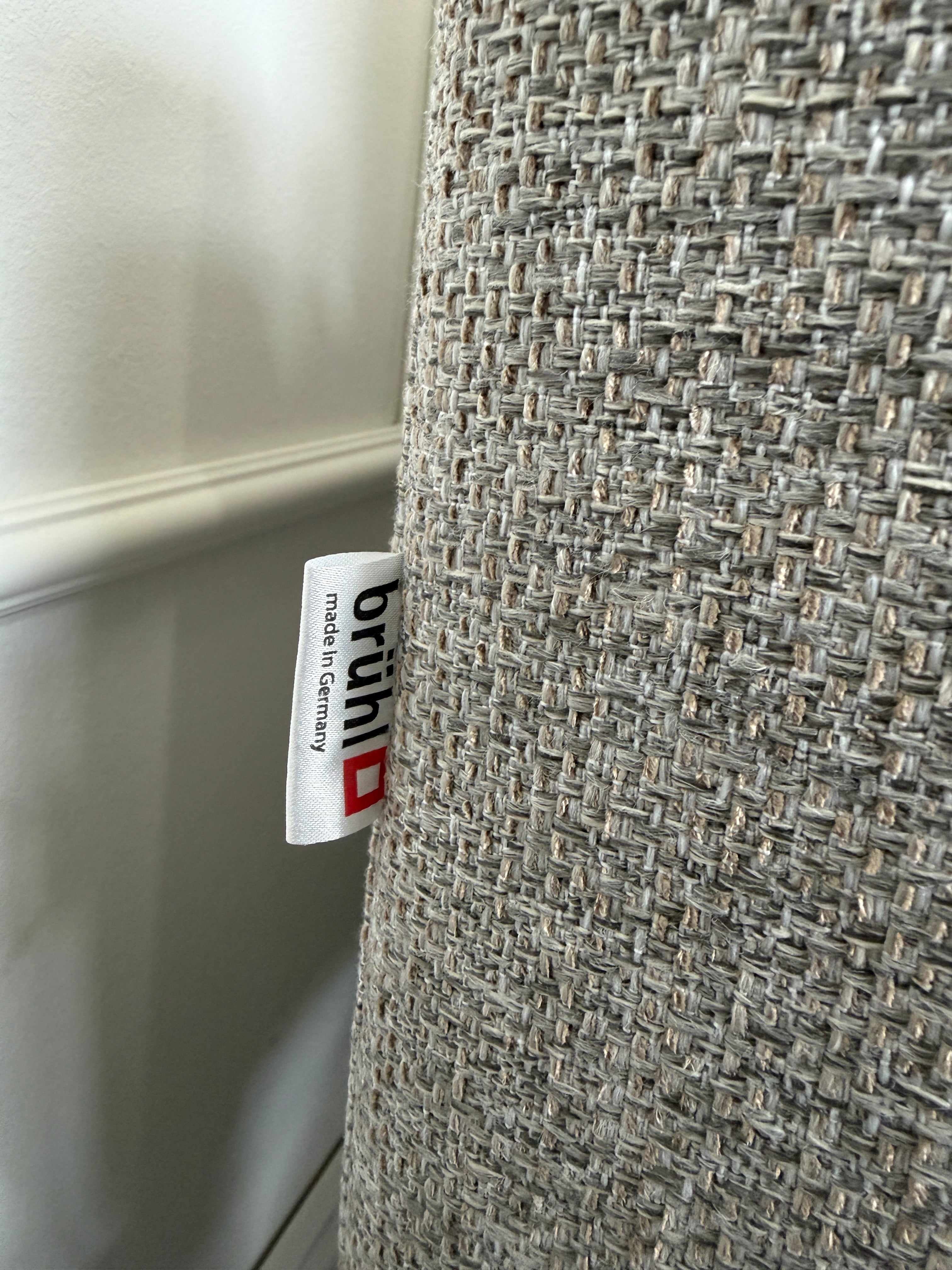 Gebrauchtes graues Brühl Alba Designer Stoff Sofa vor einer Wand, stilvoll und modern eingerichtet