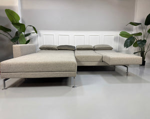 Gebrauchtes graues Brühl Moule Designer Stoff Sofa vor einer Wand, stilvoll und modern eingerichtet.