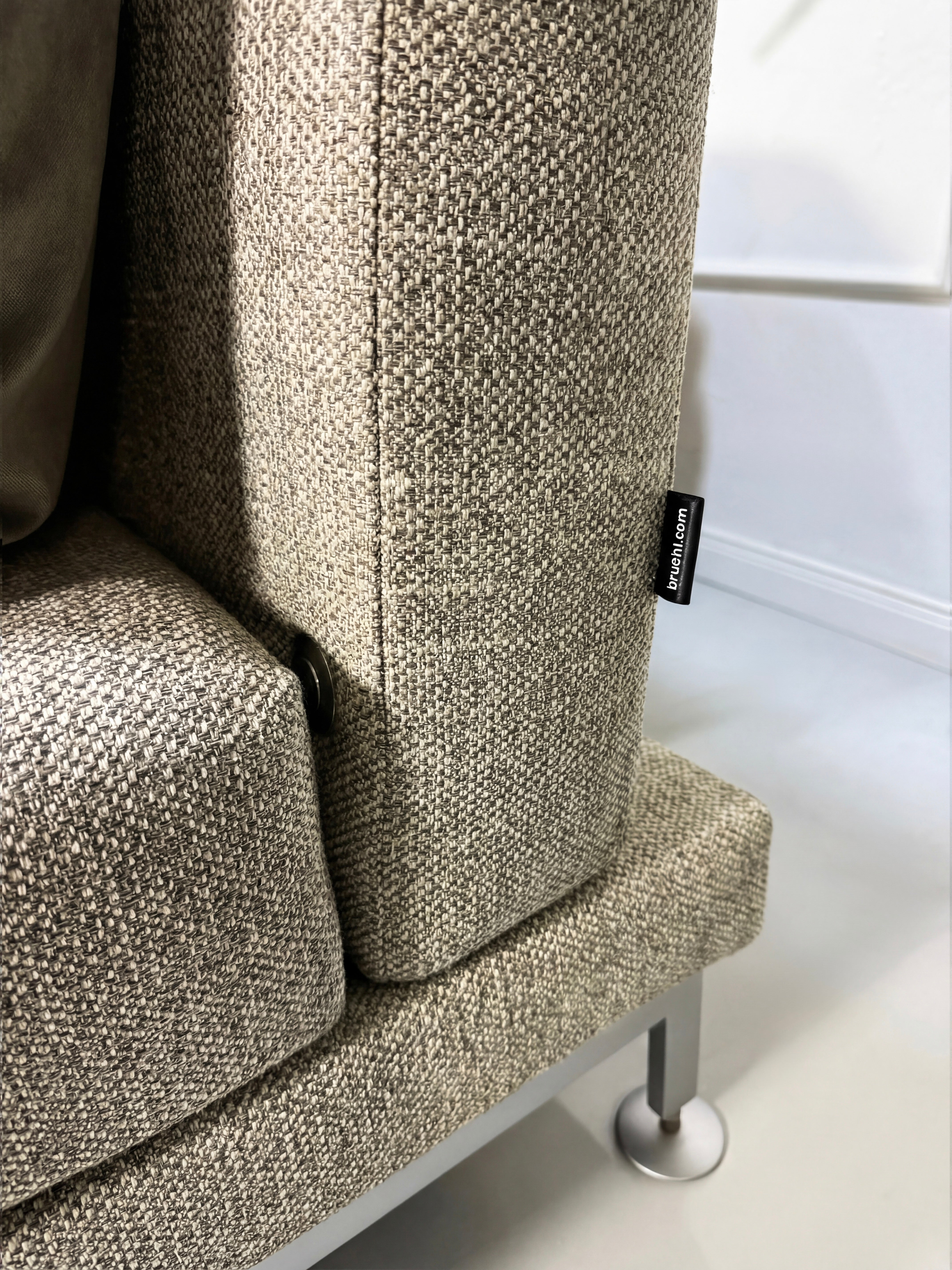 Gebrauchtes graues Brühl Moule Designer Stoff Sofa vor einer Wand, stilvoll und modern eingerichtet.