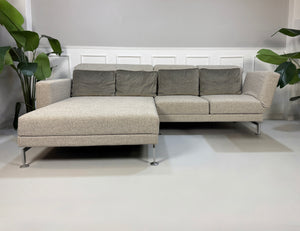Gebrauchtes graues Brühl Moule Designer Stoff Sofa vor einer Wand, stilvoll und modern eingerichtet.