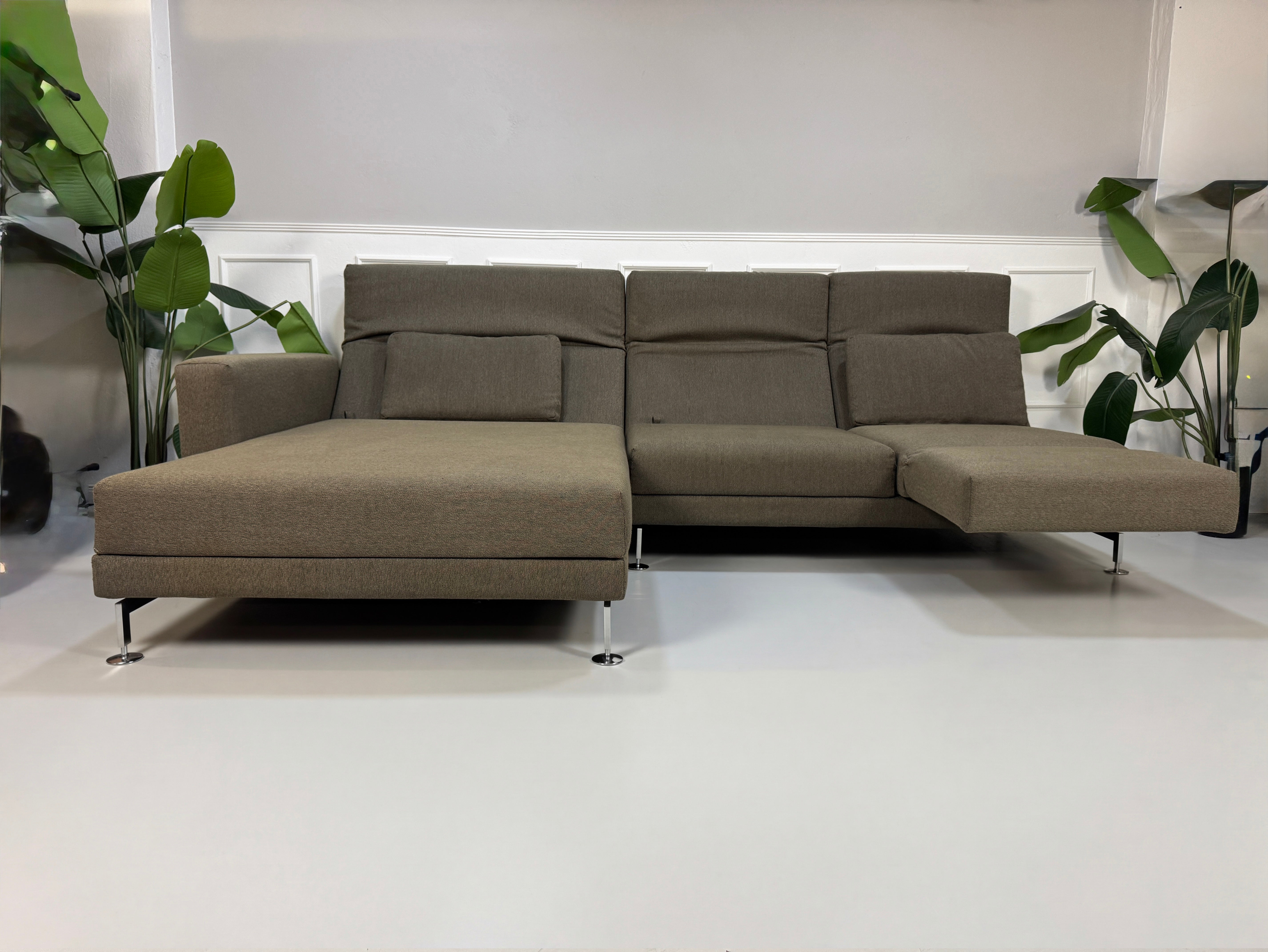 Gebrauchtes braunes Brühl Moule Designer Stoff Sofa vor einer Wand, stilvoll und modern eingerichtet.
