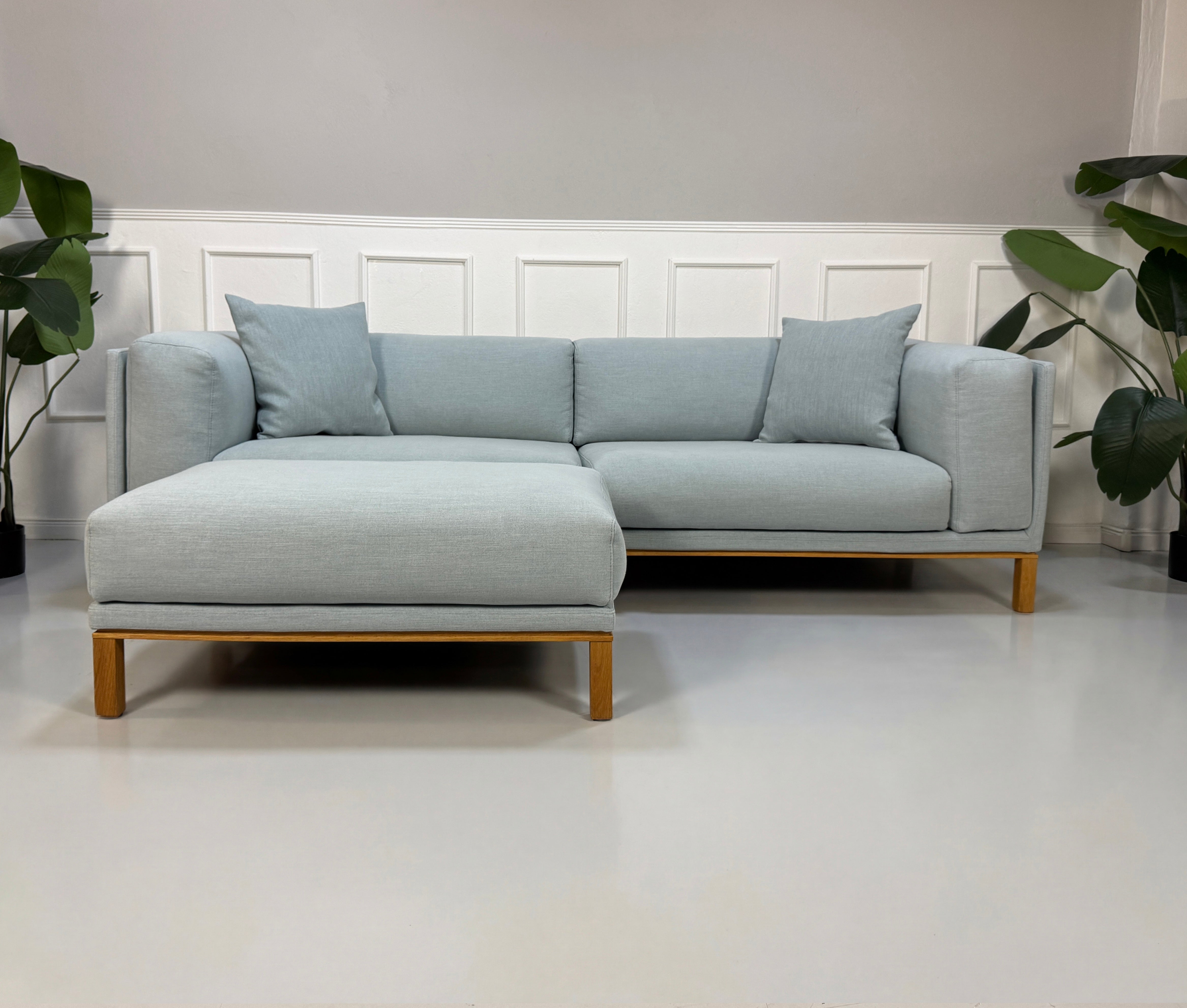 Gebrauchtes blaues Bolia Cosy Designer Stoff Sofa mit Hocker vor einer Wand, stilvoll und modern eingerichtet.