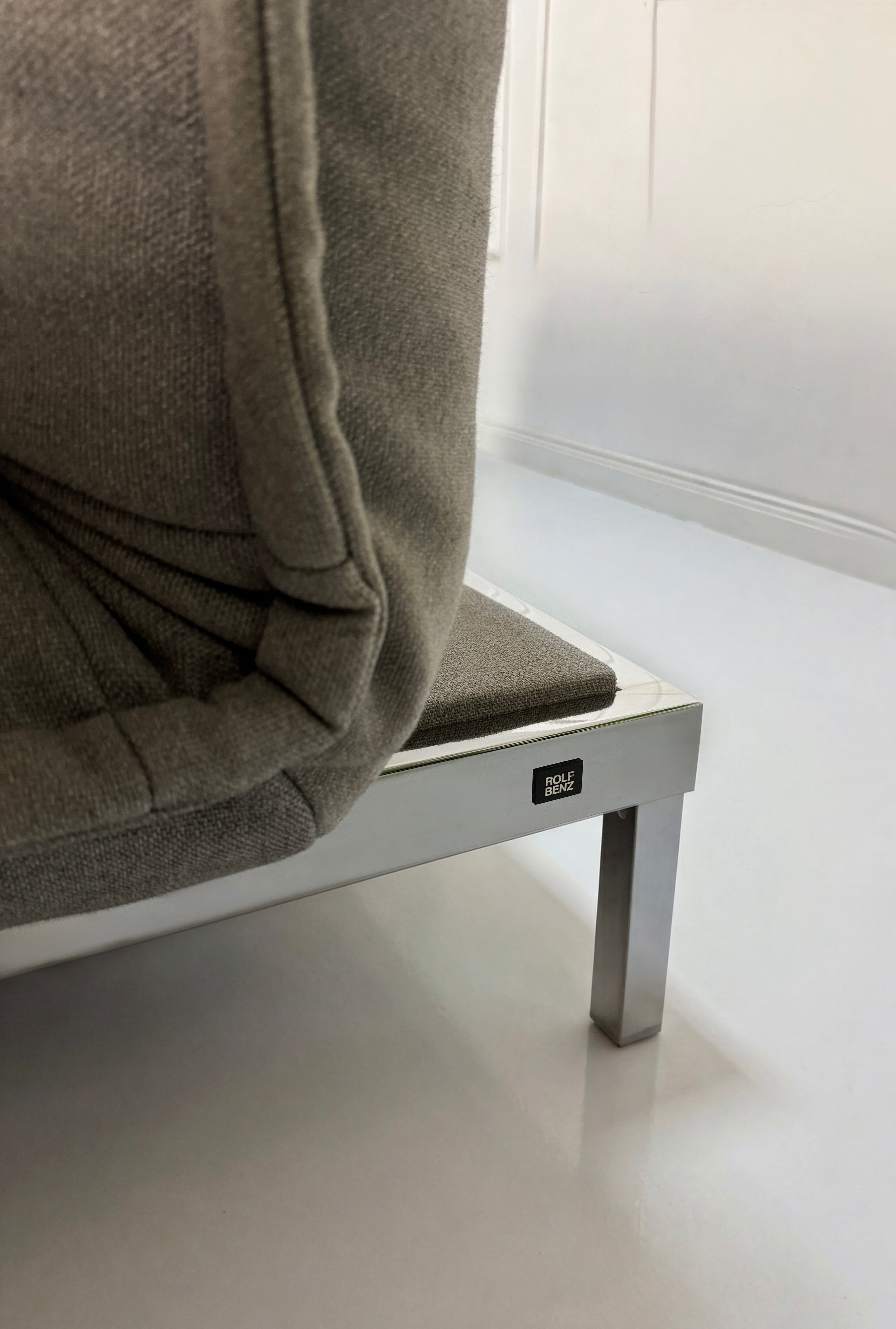 Gebrauchtes graues Rolf Benz Nova Designer Stoff Sofa vor einer Wand, stilvoll und modern eingerichtet.