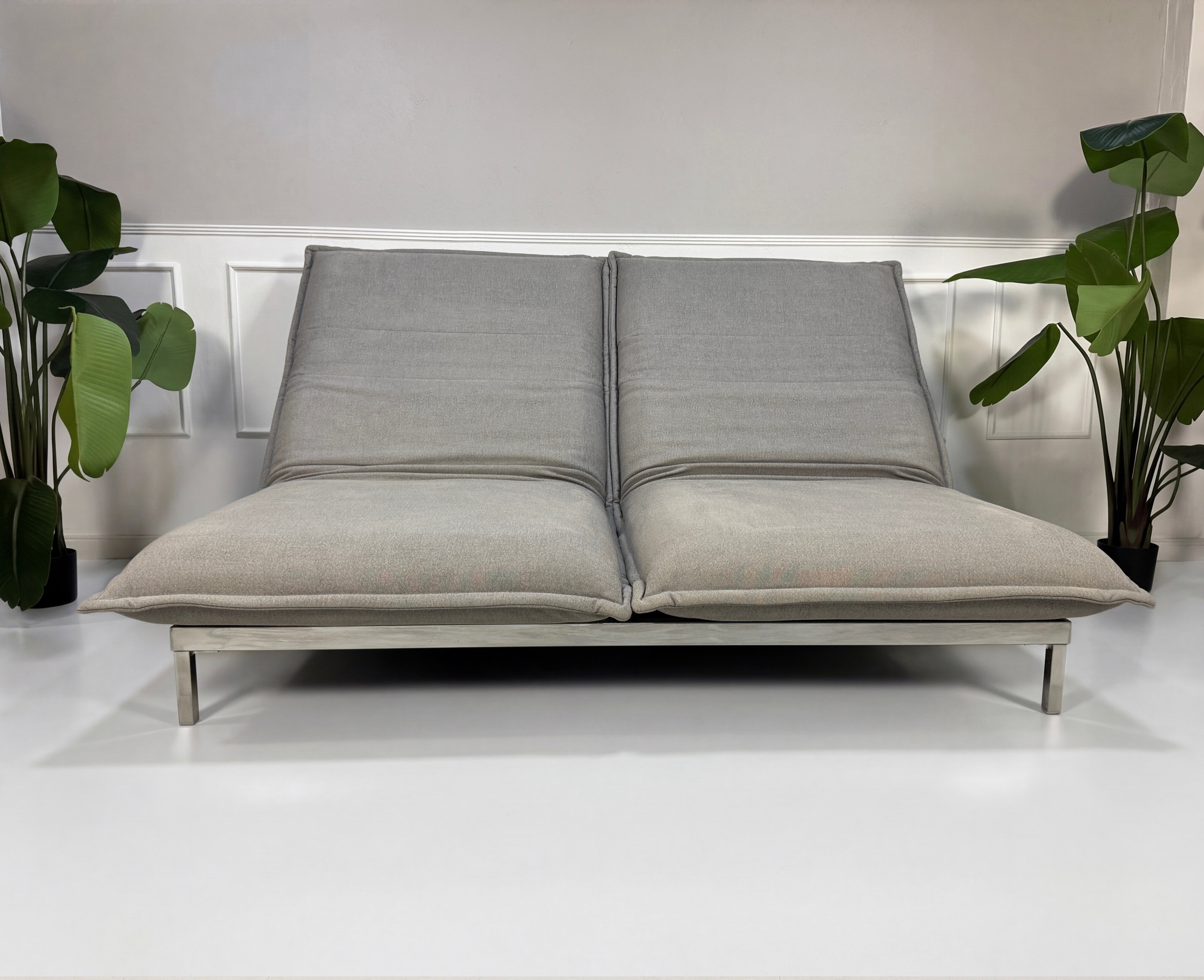 Gebrauchtes graues Rolf Benz Nova Designer Stoff Sofa vor einer Wand, stilvoll und modern eingerichtet.