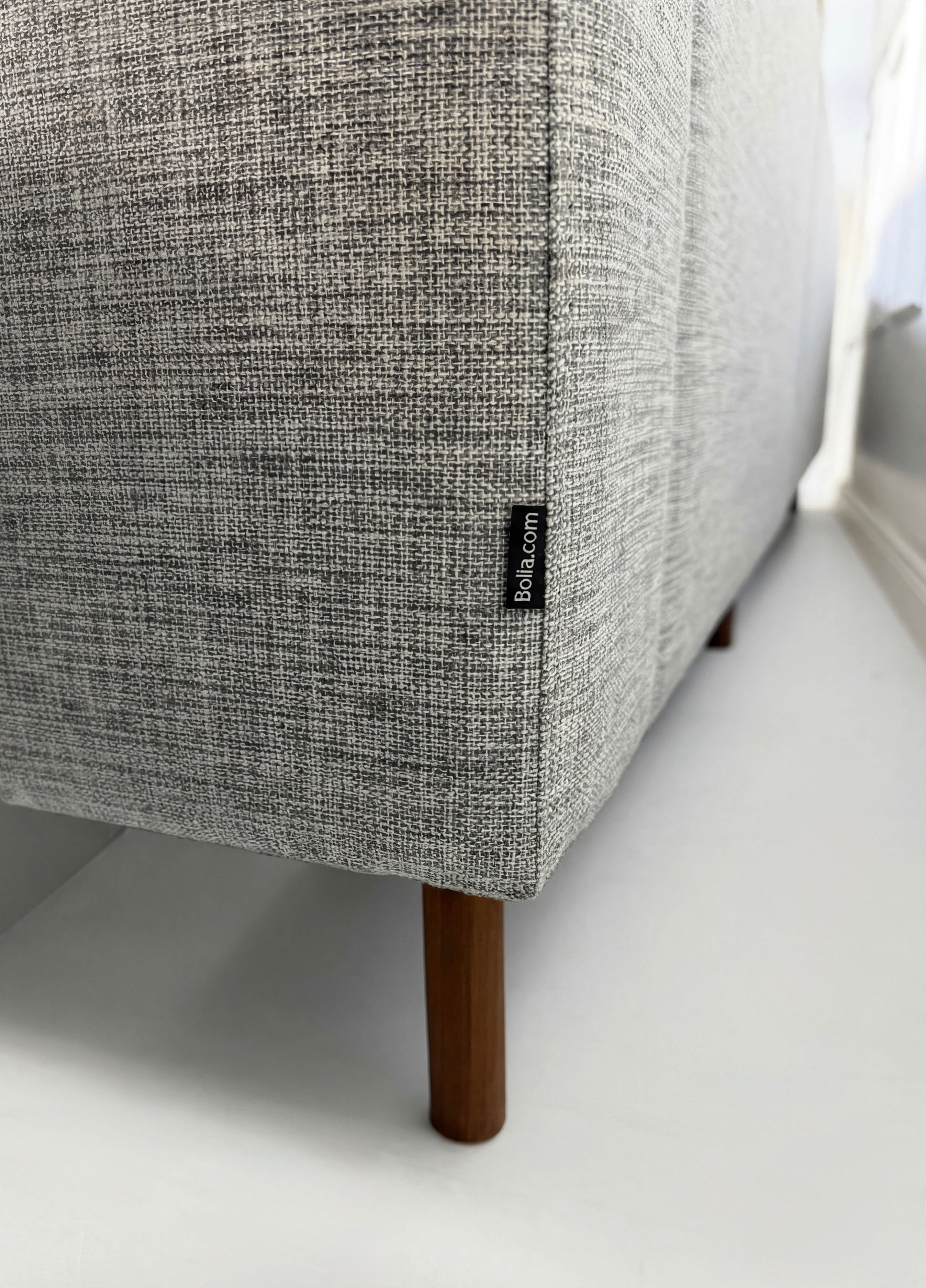 Gebrauchtes graues Bolia Scandinavia Designer Stoff Sofa vor einer Wand, stilvoll und modern eingerichtet.