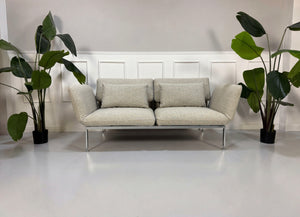 Gebrauchtes graues Brühl Roro Designer Stoff Sofa vor einer Wand, stilvoll und modern eingerichtet.