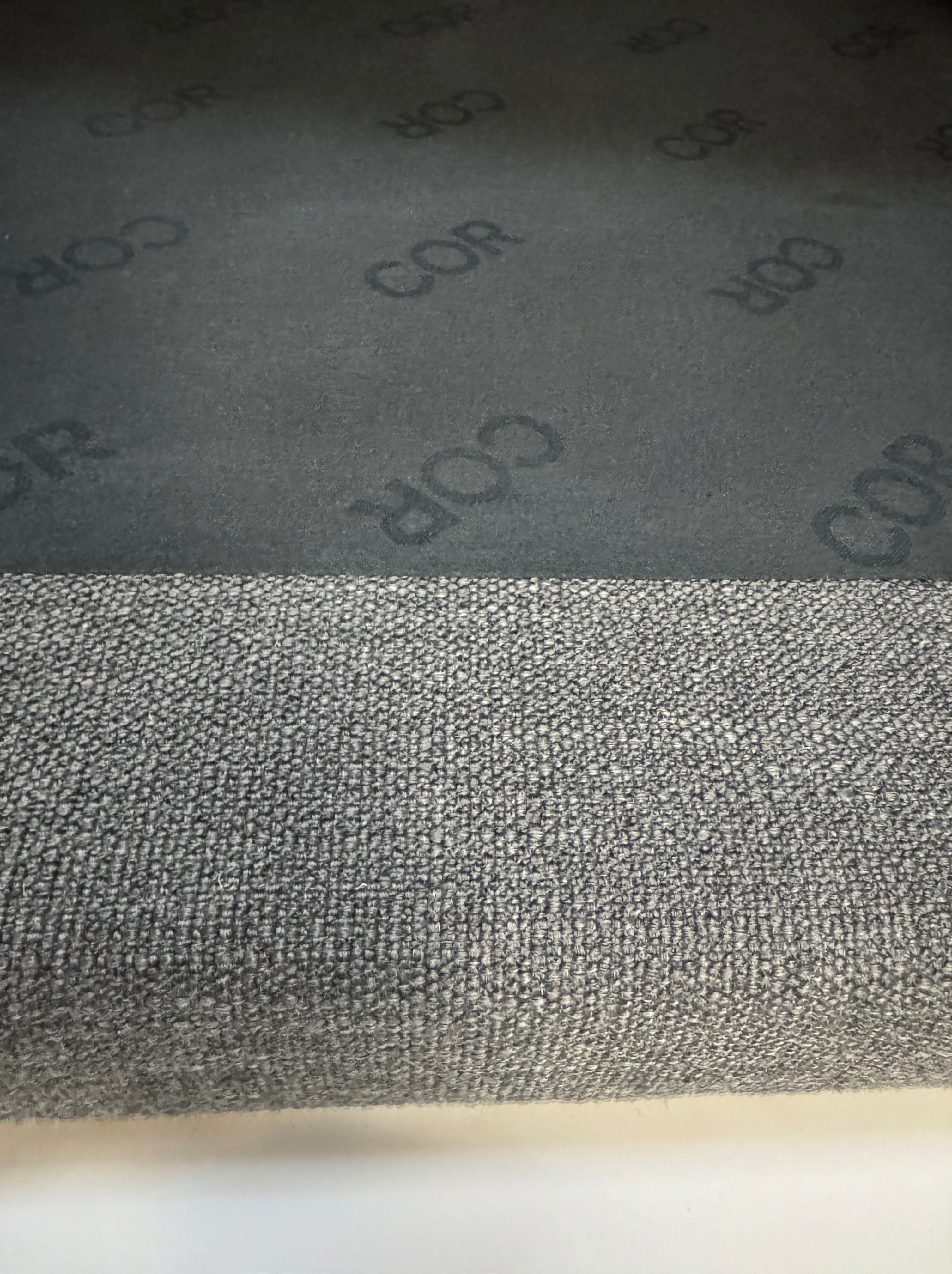 Gebrauchtes graues COR Pilotis Designer Stoff Sofa vor einer Wand, stilvoll und modern eingerichtet.