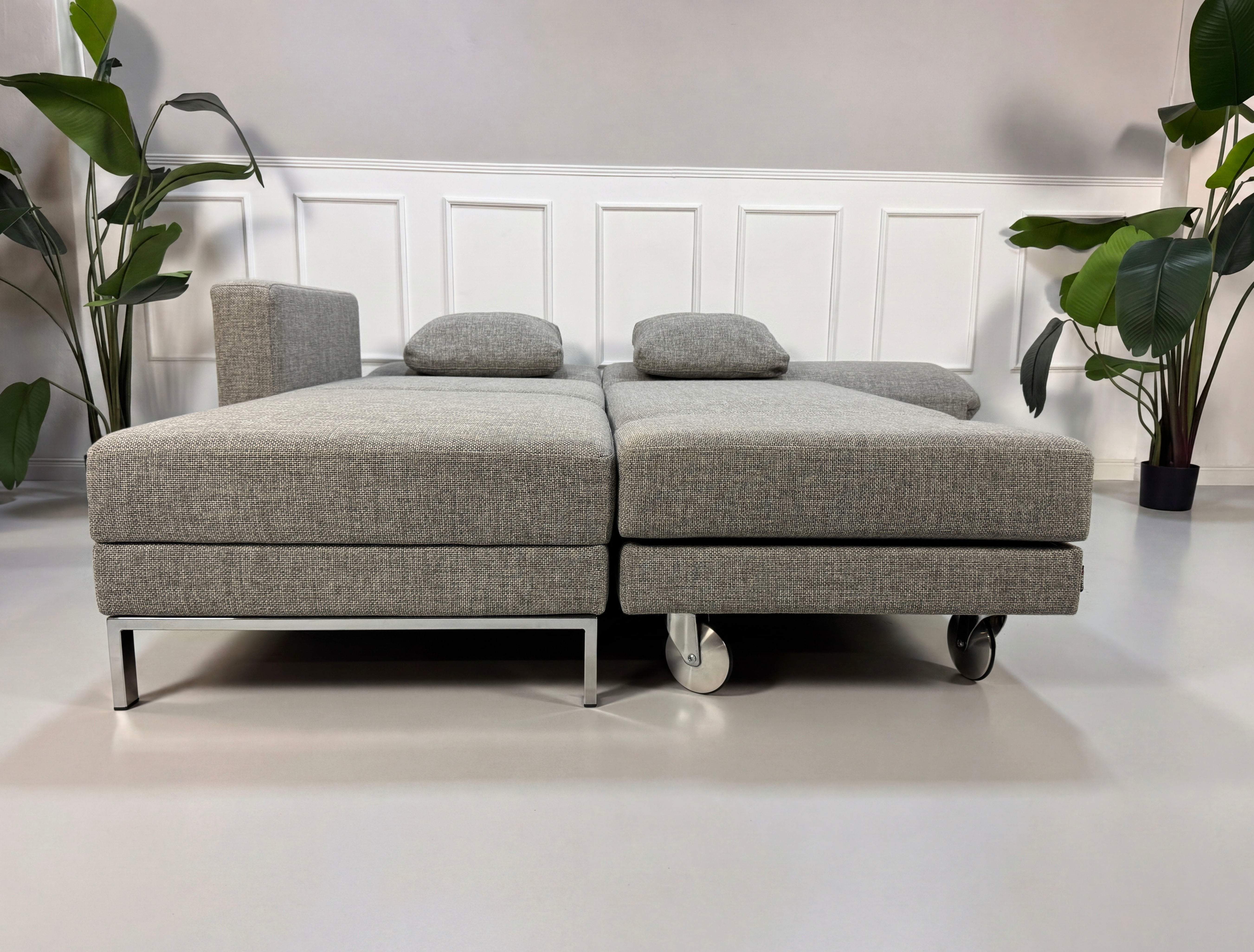 Graues Ausstellungsstück Brühl Four Two  Designer Stoff Sofa vor einer Wand, stilvoll und modern eingerichtet.