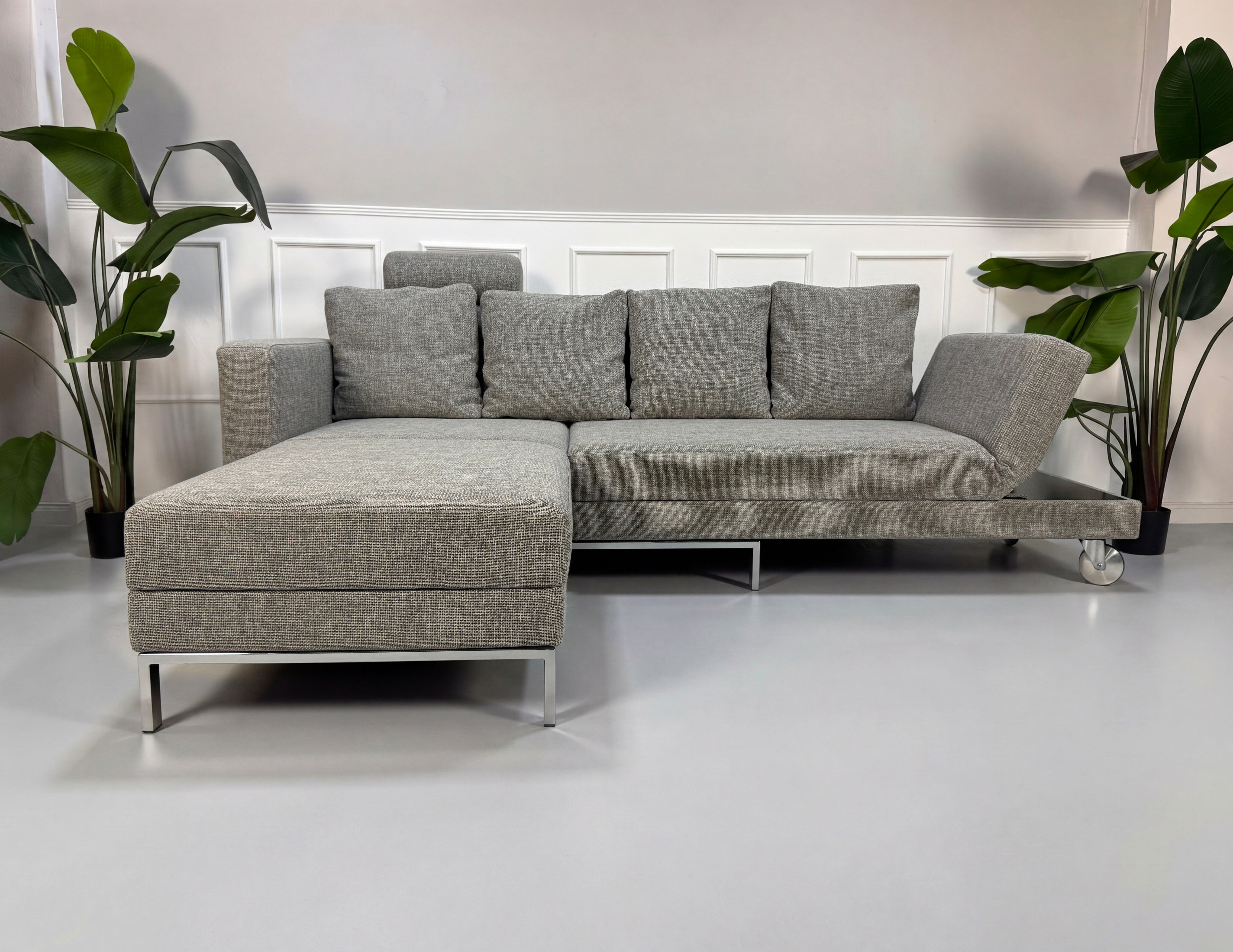 Graues Ausstellungsstück Brühl Four Two  Designer Stoff Sofa vor einer Wand, stilvoll und modern eingerichtet.