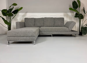 Gebrauchtes graues Brühl Four Two Designer Stoff Sofa vor einer Wand, stilvoll und modern eingerichtet.