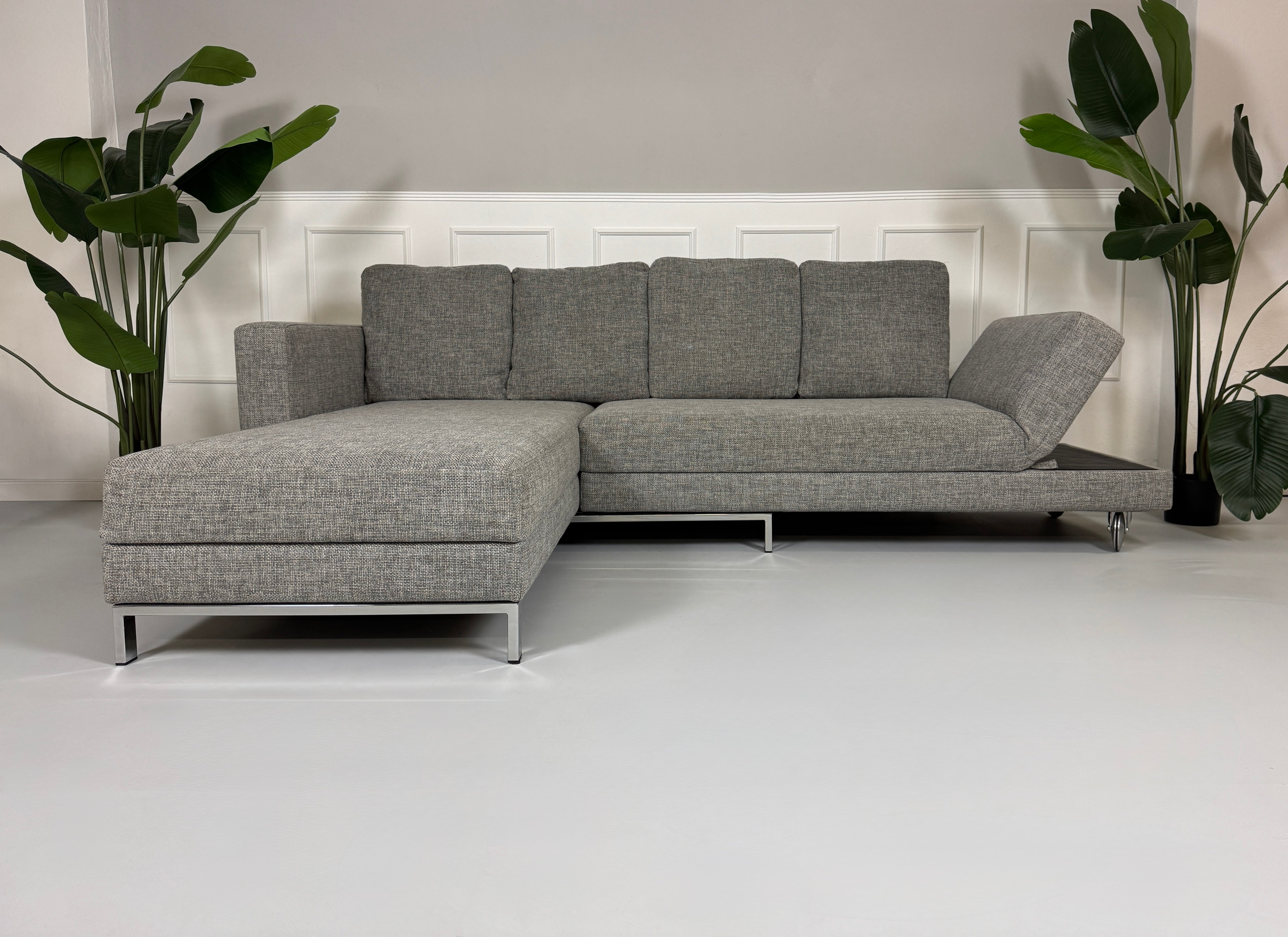 Gebrauchtes graues Brühl Four Two Designer Stoff Sofa vor einer Wand, stilvoll und modern eingerichtet.