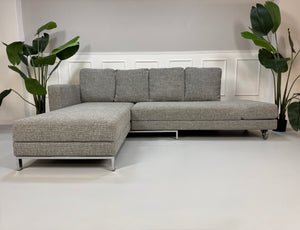 Gebrauchtes graues Brühl Four Two Designer Stoff Sofa vor einer Wand, stilvoll und modern eingerichtet.
