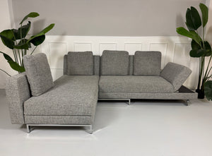 Gebrauchtes graues Brühl Four Two Designer Stoff Sofa vor einer Wand, stilvoll und modern eingerichtet.