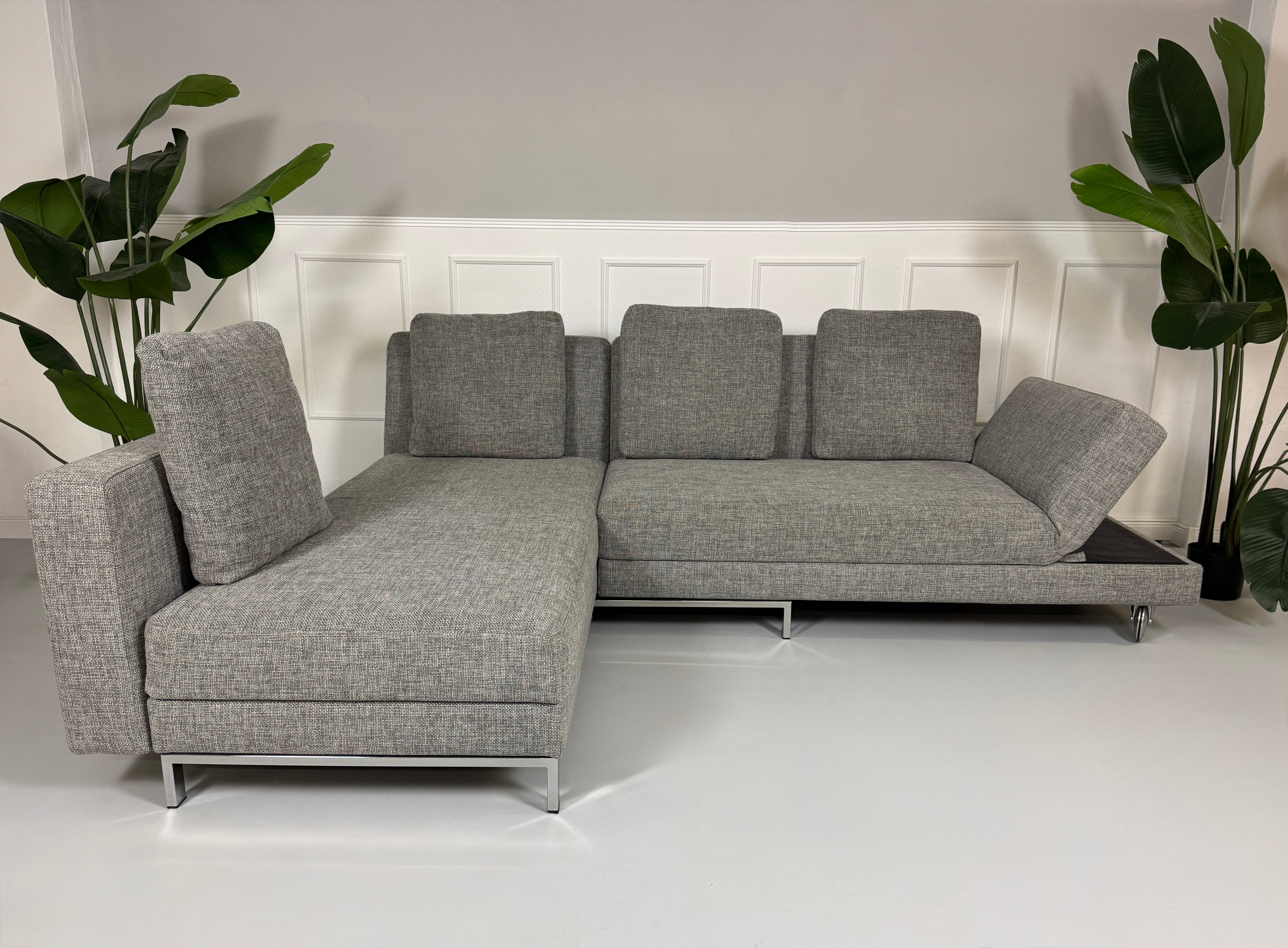 Gebrauchtes graues Brühl Four Two Designer Stoff Sofa vor einer Wand, stilvoll und modern eingerichtet.