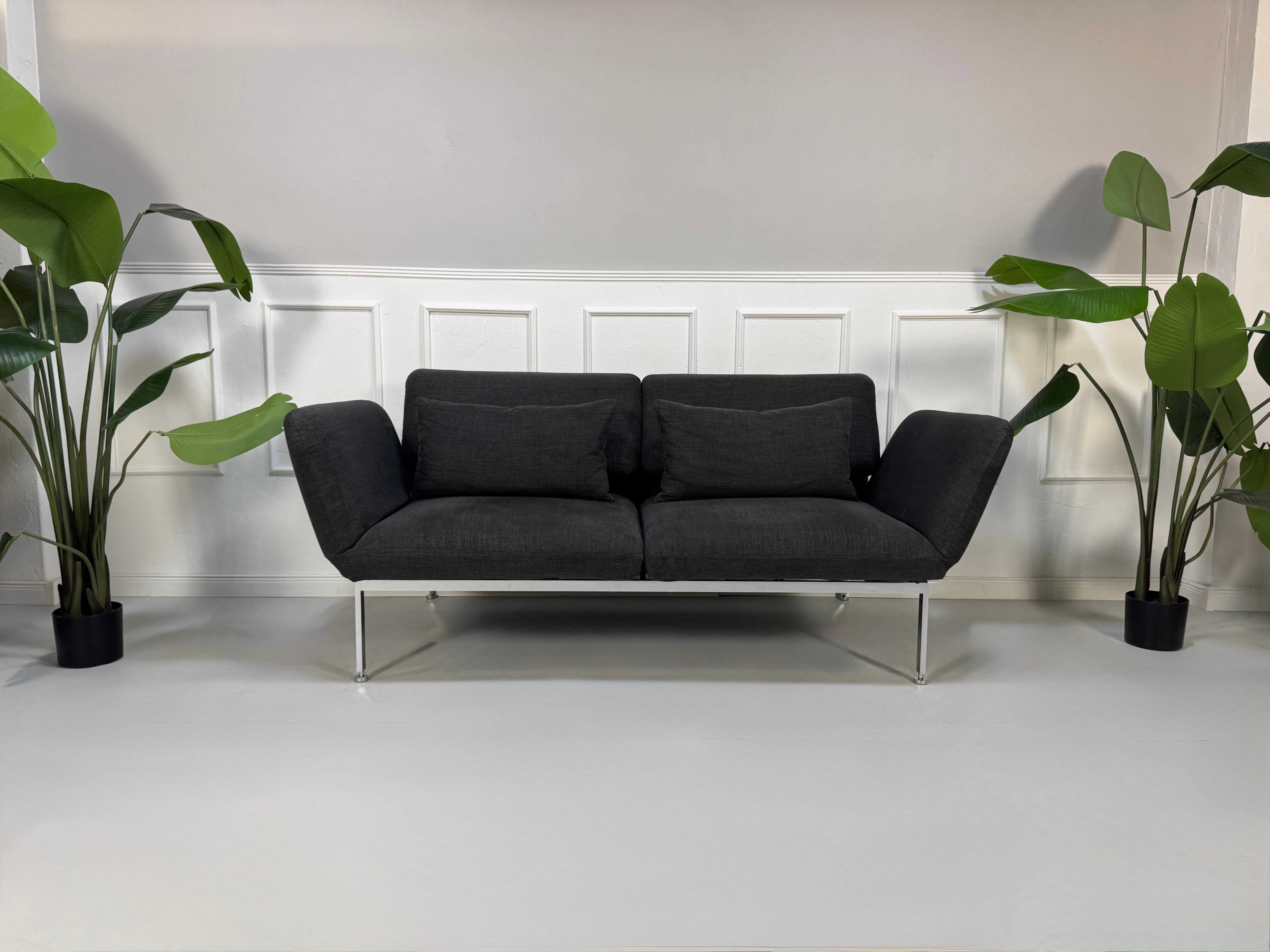 Gebrauchtes graues Brühl Roro Designer Stoff Sofa vor einer Wand, stilvoll und modern eingerichtet.