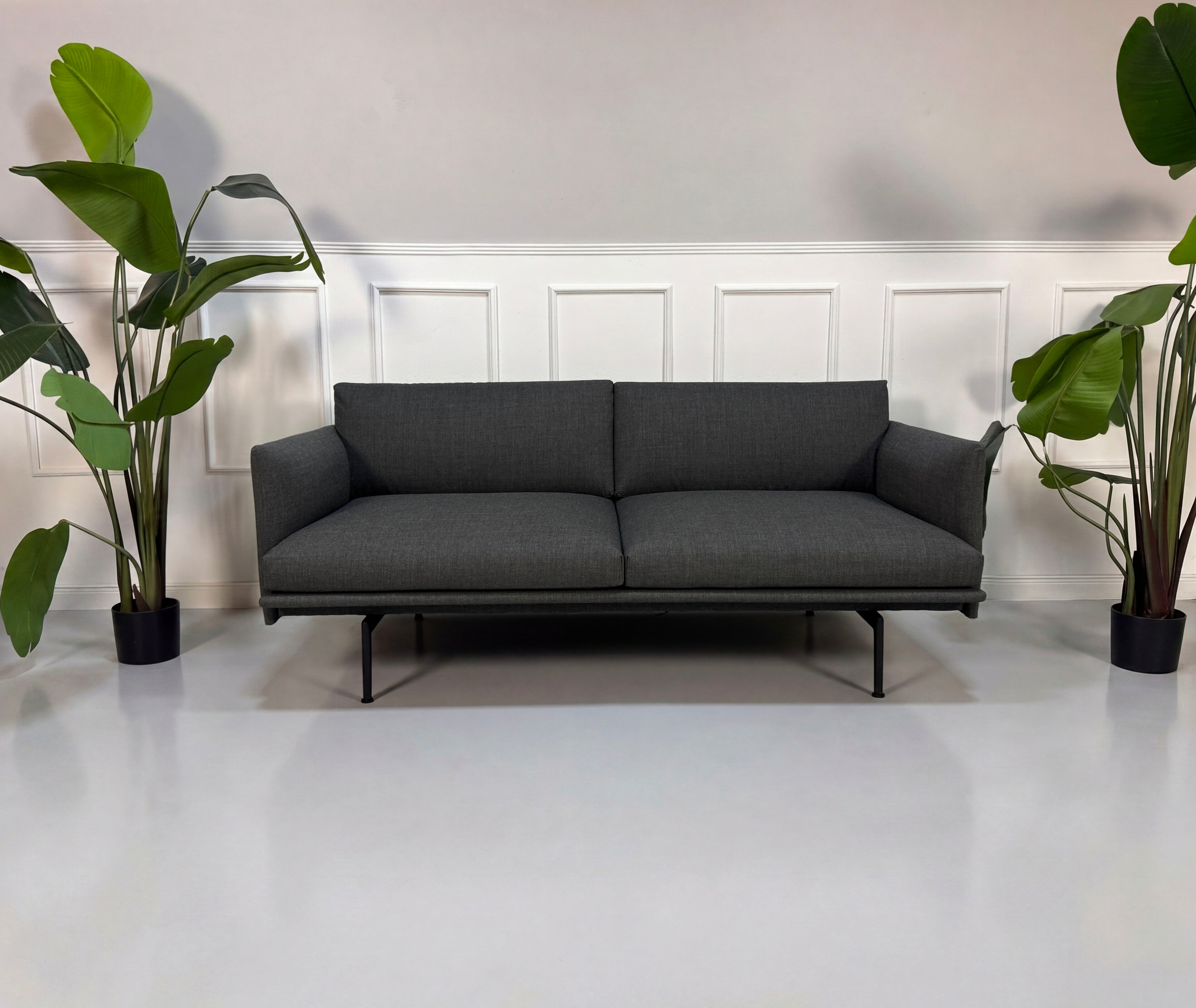 Gebrauchtes graues Muuto Outline Designer Stoff Sofa vor einer Wand, stilvoll und modern eingerichtet.