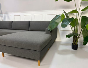 Gebrauchtes graues Bolia Scandinavia Designer Stoff Sofa vor einer Wand, stilvoll und modern eingerichtet.