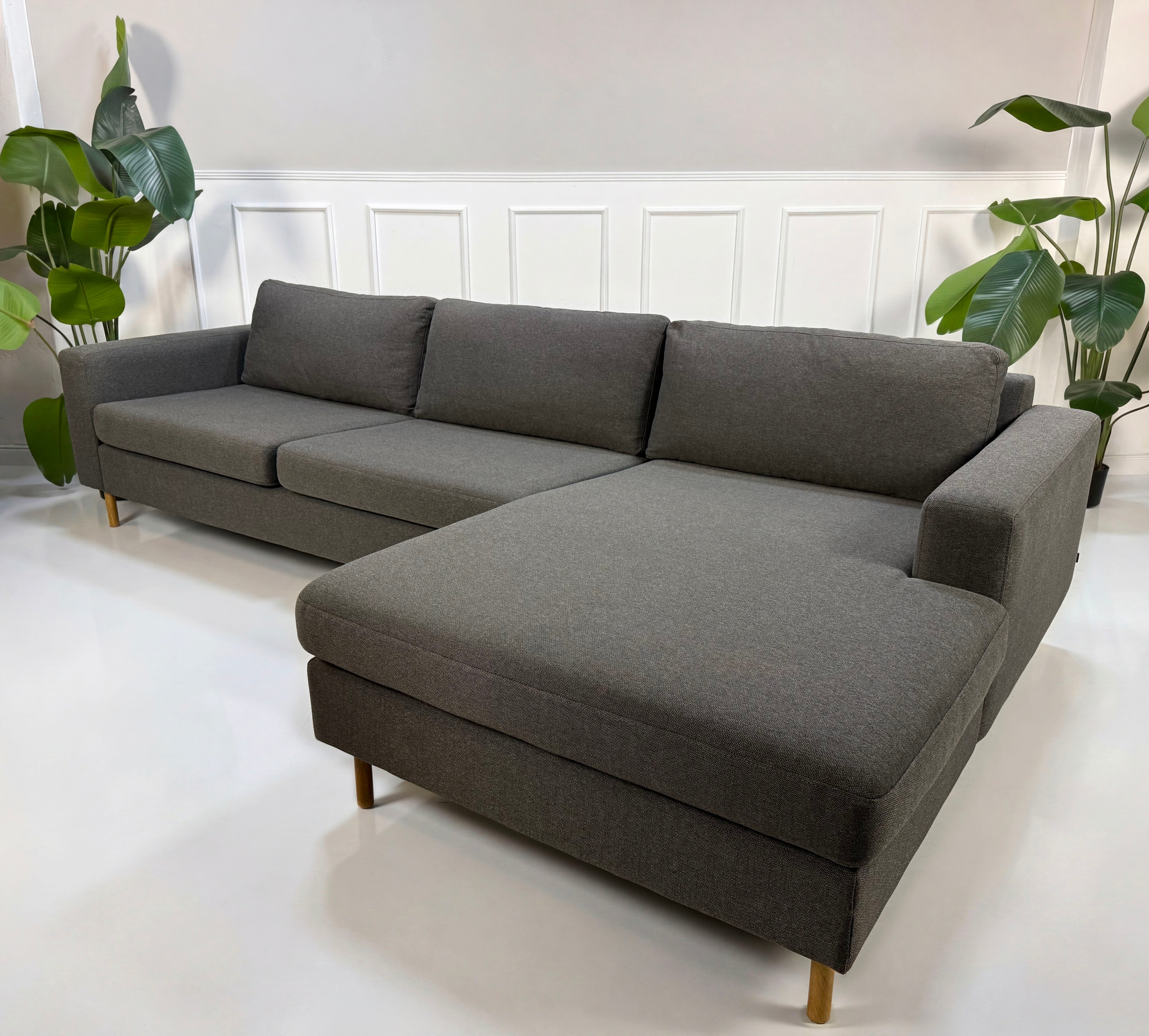 Gebrauchtes graues Bolia Scandinavia Designer Stoff Sofa vor einer Wand, stilvoll und modern eingerichtet.