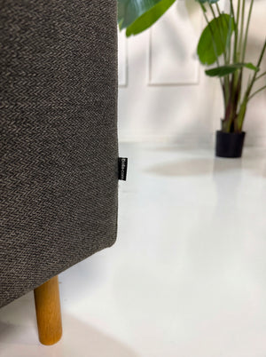 Gebrauchtes graues Bolia Scandinavia Designer Stoff Sofa vor einer Wand, stilvoll und modern eingerichtet.