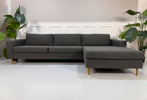 Gebrauchtes graues Bolia Scandinavia Designer Stoff Sofa vor einer Wand, stilvoll und modern eingerichtet.