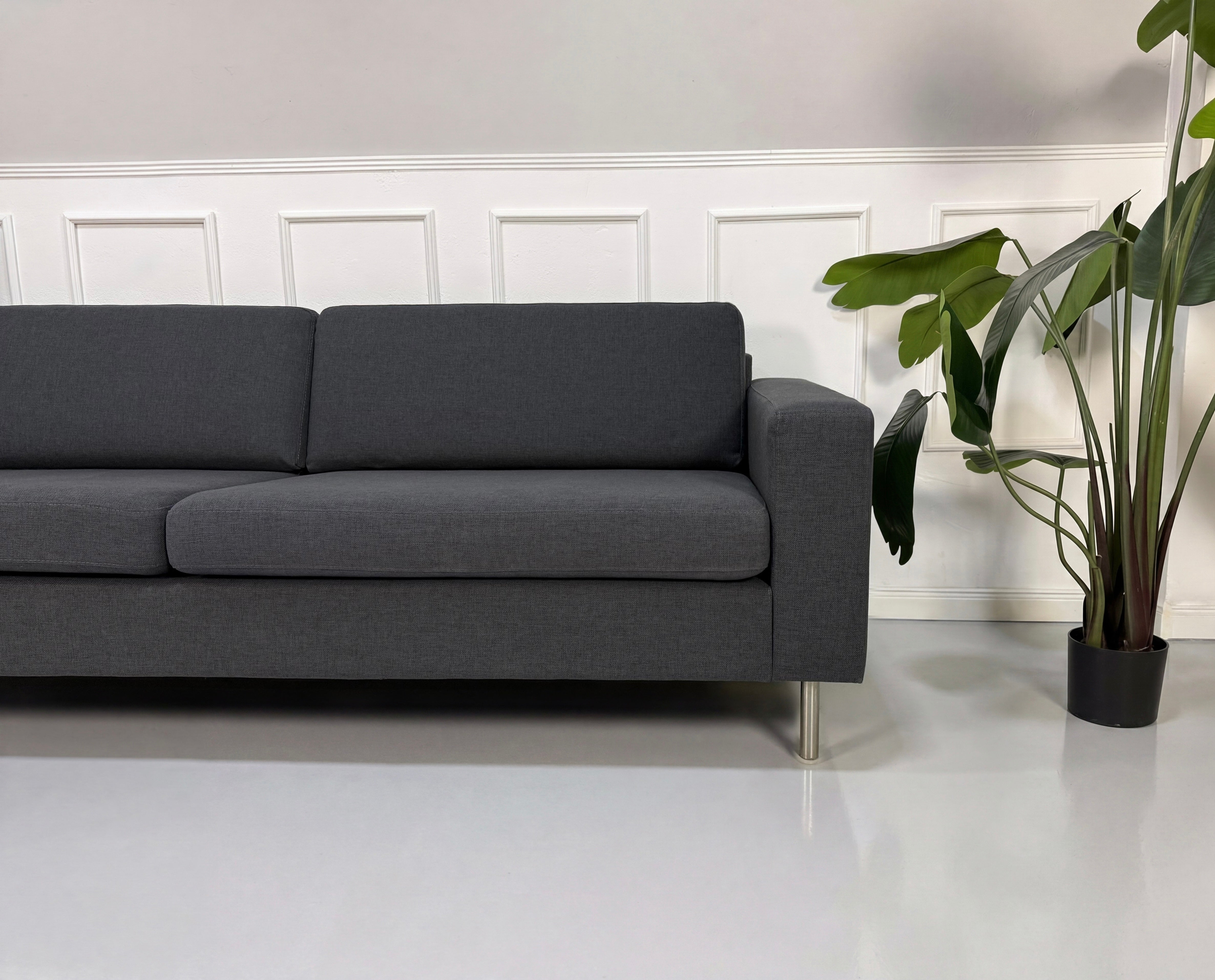 Gebrauchtes graues Bolia Scandinavia Designer Stoff Sofa vor einer Wand, stilvoll und modern eingerichtet.