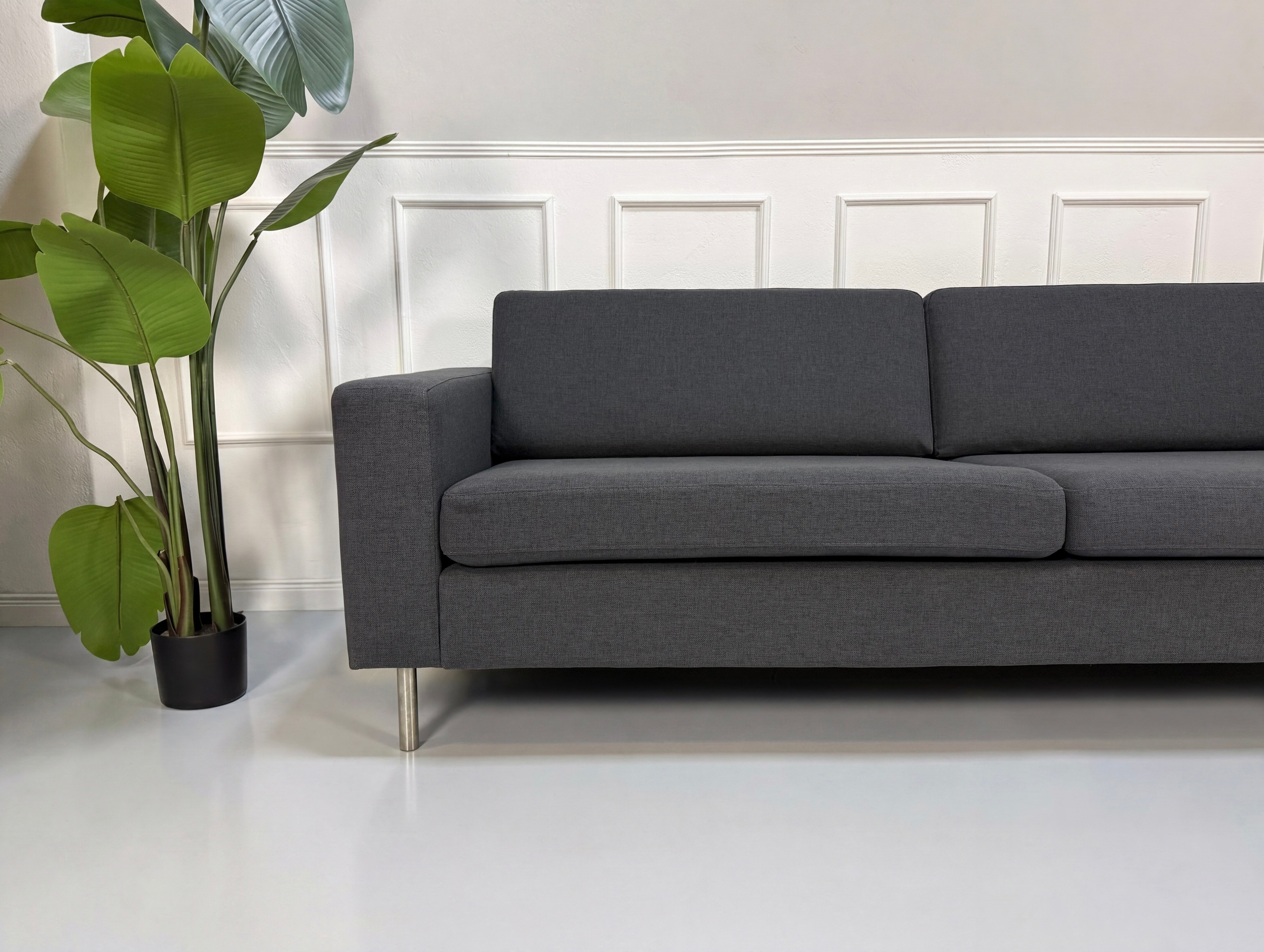 Gebrauchtes graues Bolia Scandinavia Designer Stoff Sofa vor einer Wand, stilvoll und modern eingerichtet.
