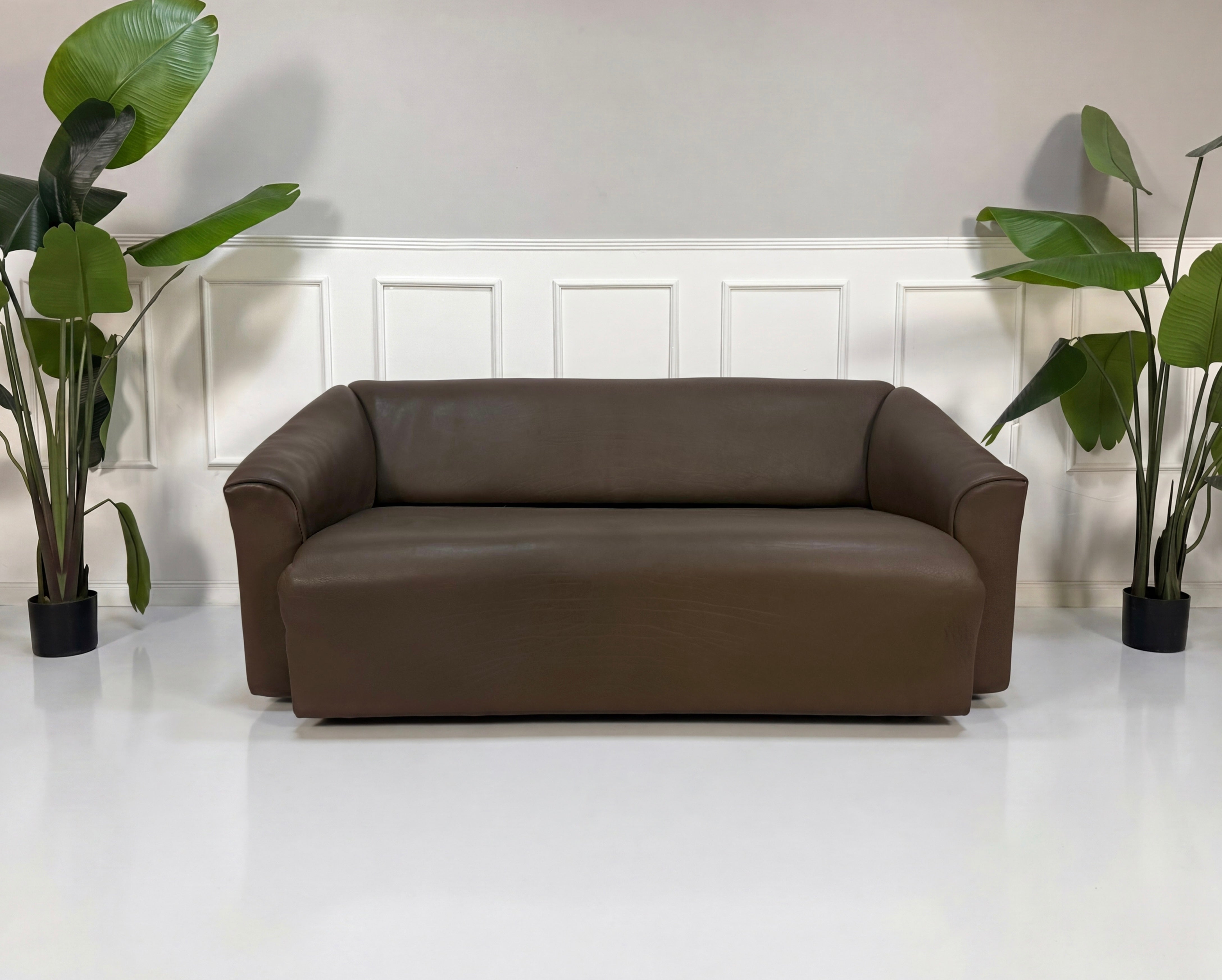 Gebrauchtes braunes DeSede DS47 Designer Leder Sofa vor einer Wand, stilvoll und modern eingerichtet.