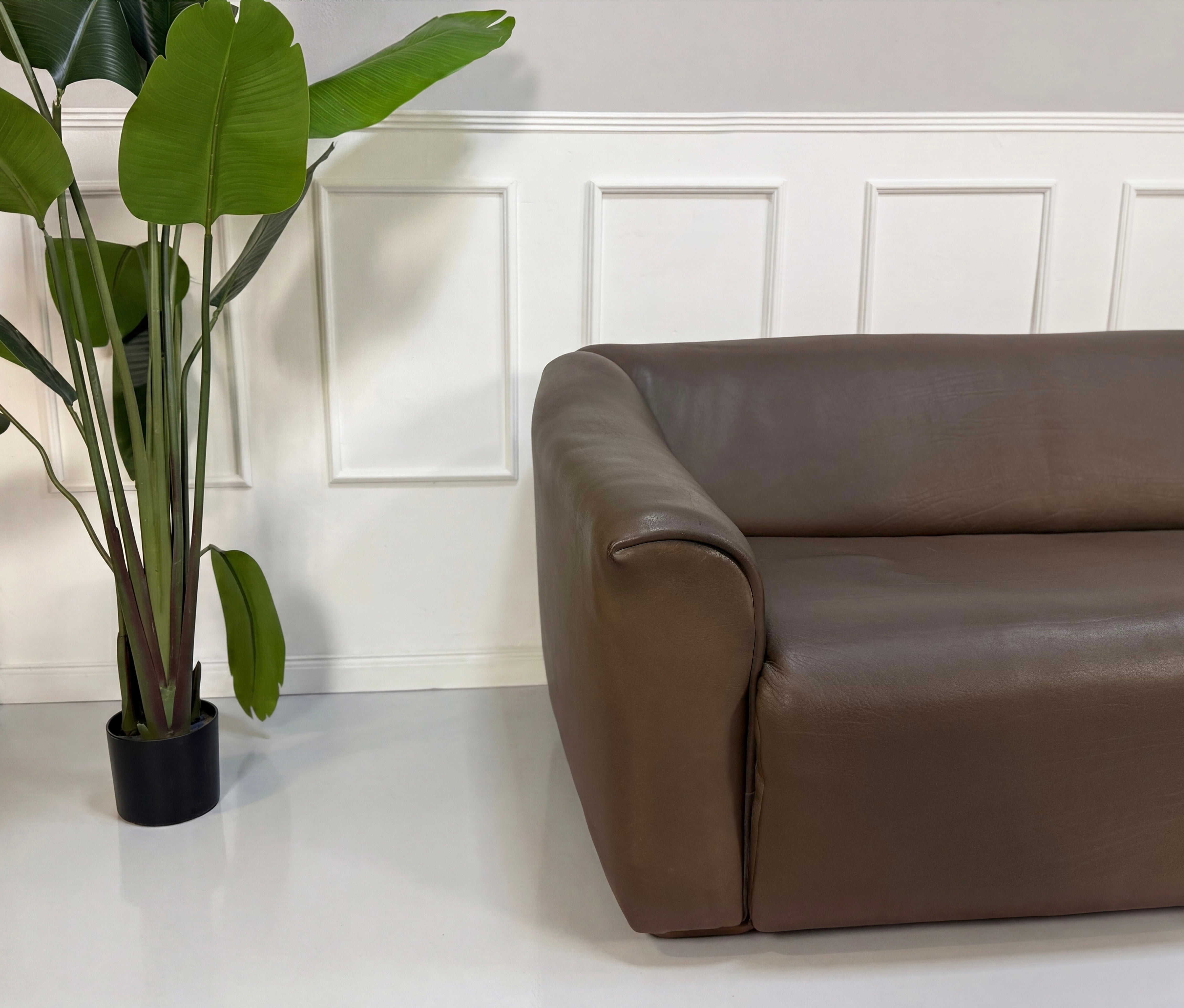 Gebrauchtes braunes DeSede DS47 Designer Leder Sofa vor einer Wand, stilvoll und modern eingerichtet.
