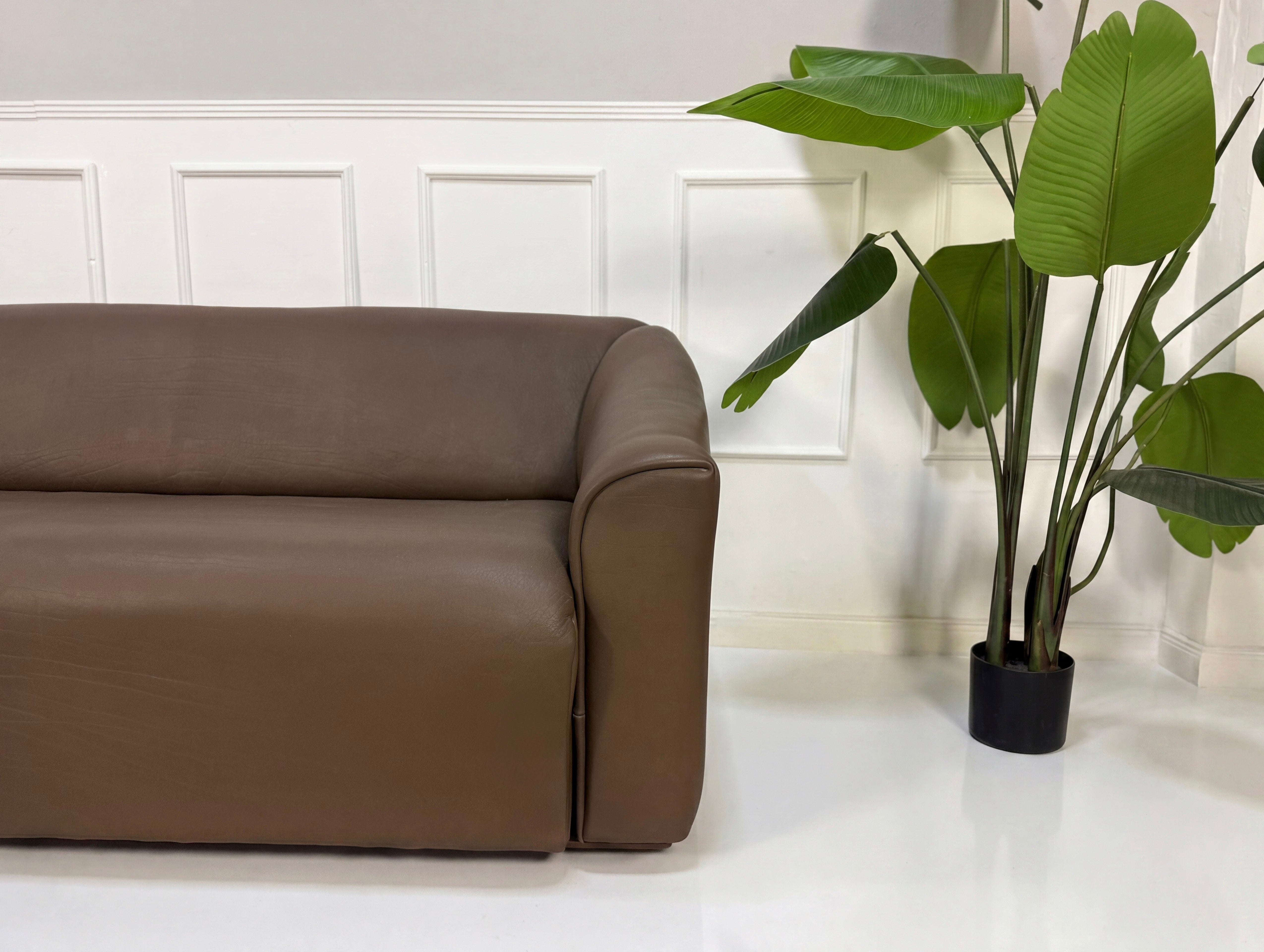 Gebrauchtes braunes DeSede DS47 Designer Leder Sofa vor einer Wand, stilvoll und modern eingerichtet.