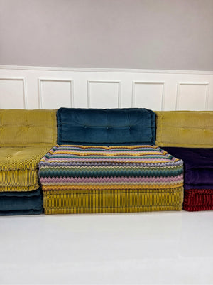 Gebrauchtes buntes Roche Bobois Mah Jong Designer Stoff Sofa vor einer Wand, stilvoll und modern eingerichtet.