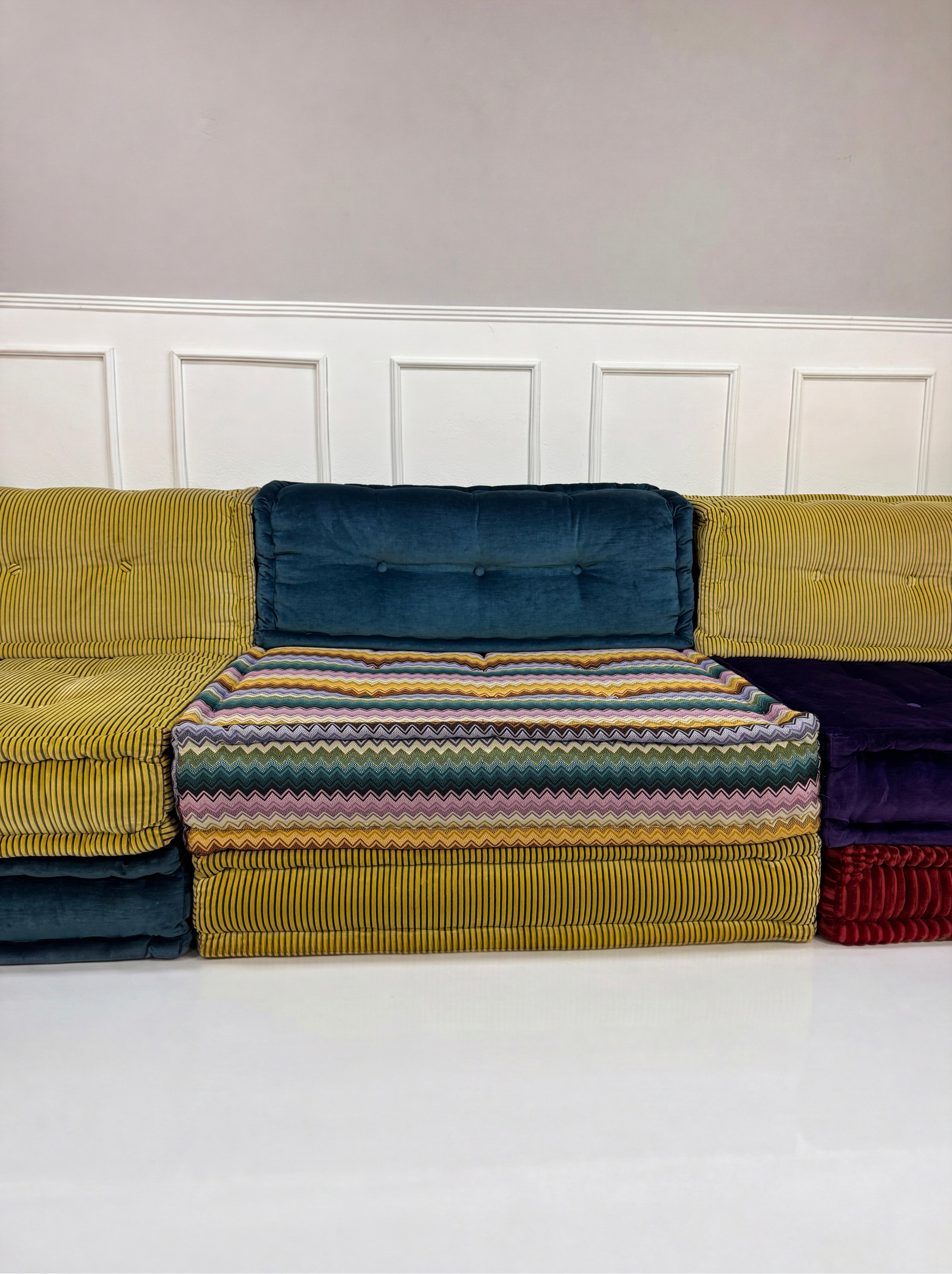 Gebrauchtes buntes Roche Bobois Mah Jong Designer Stoff Sofa vor einer Wand, stilvoll und modern eingerichtet.