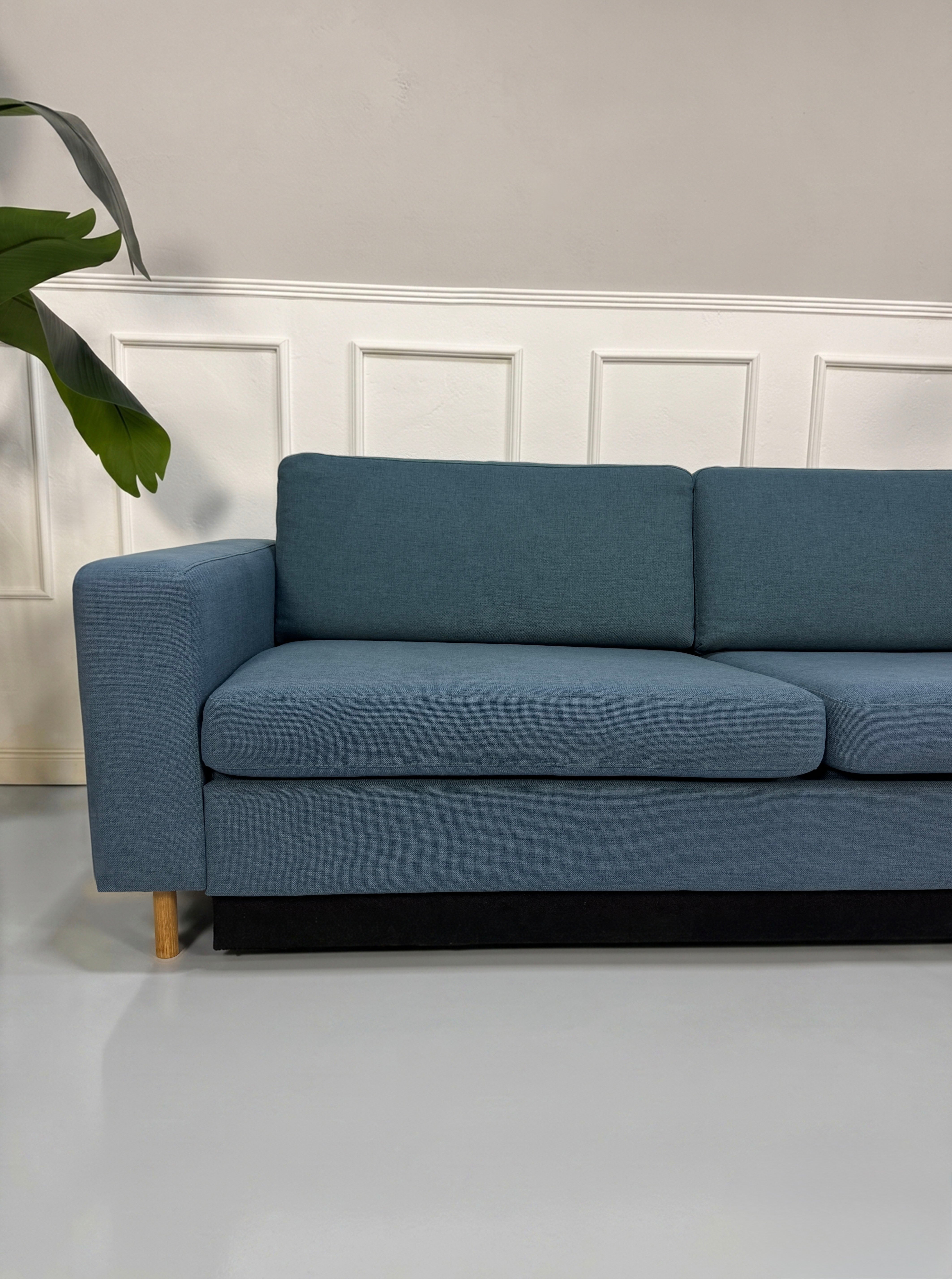 Gebrauchtes blaues Bolia Scandinavia Designer Stoff Sofa vor einer Wand, stilvoll und modern eingerichtet.