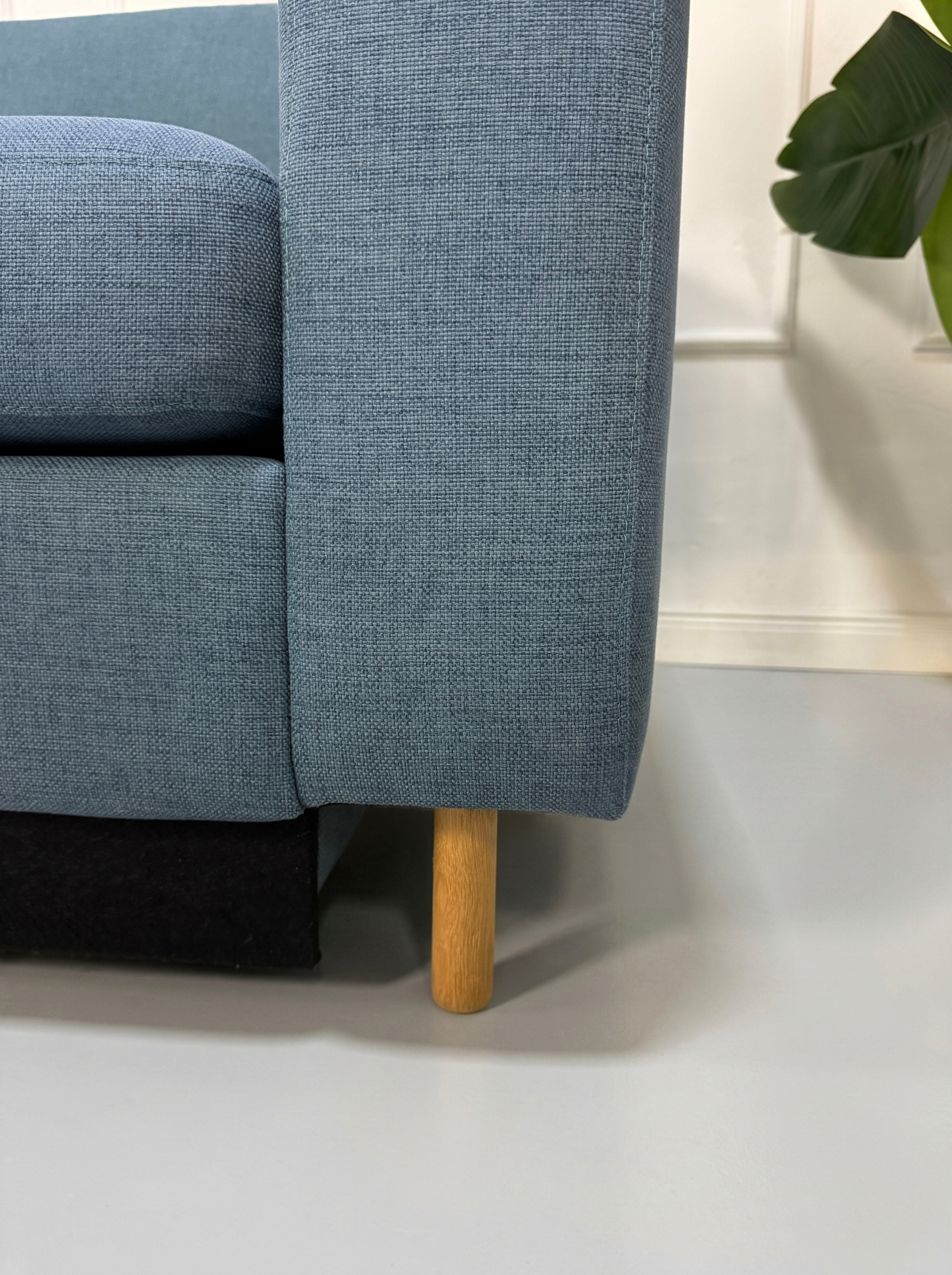 Gebrauchtes blaues Bolia Scandinavia Designer Stoff Sofa vor einer Wand, stilvoll und modern eingerichtet.
