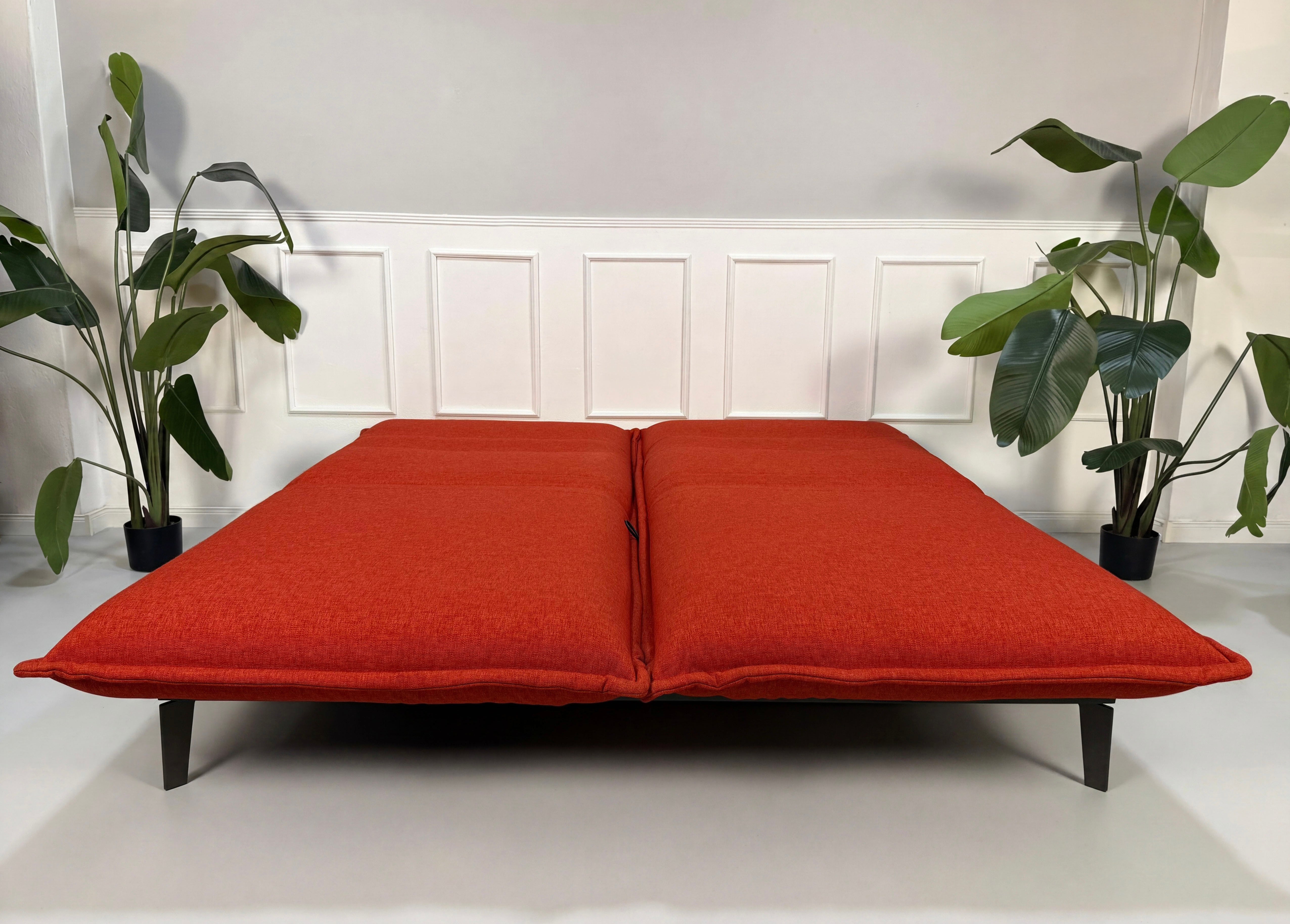 Gebrauchtes orange Rolf Benz Nova Designer Stoff Sofa vor einer Wand, stilvoll und modern eingerichtet.