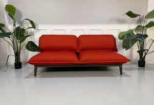 Gebrauchtes orange Rolf Benz Nova Designer Stoff Sofa vor einer Wand, stilvoll und modern eingerichtet.
