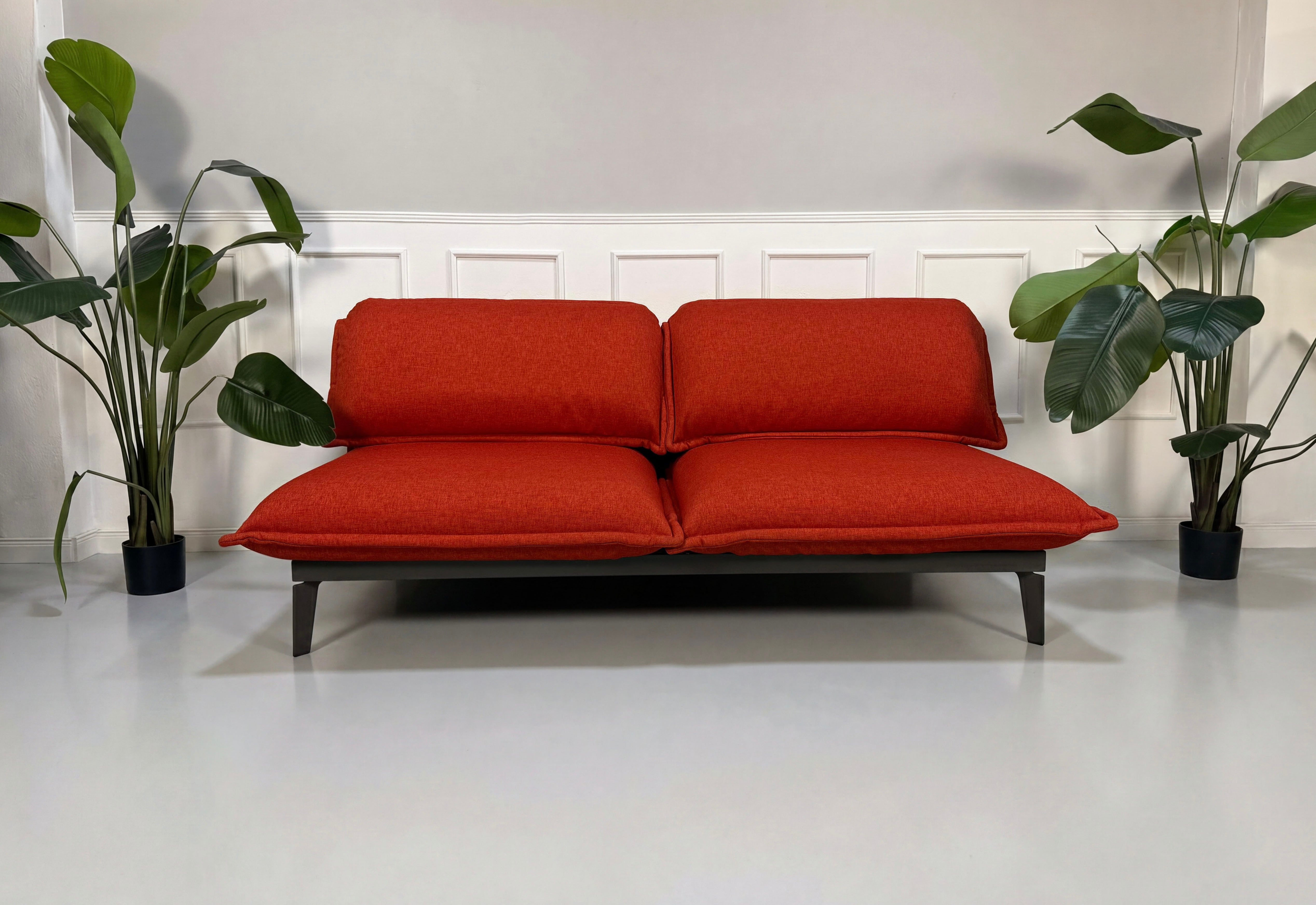 Gebrauchtes orange Rolf Benz Nova Designer Stoff Sofa vor einer Wand, stilvoll und modern eingerichtet.
