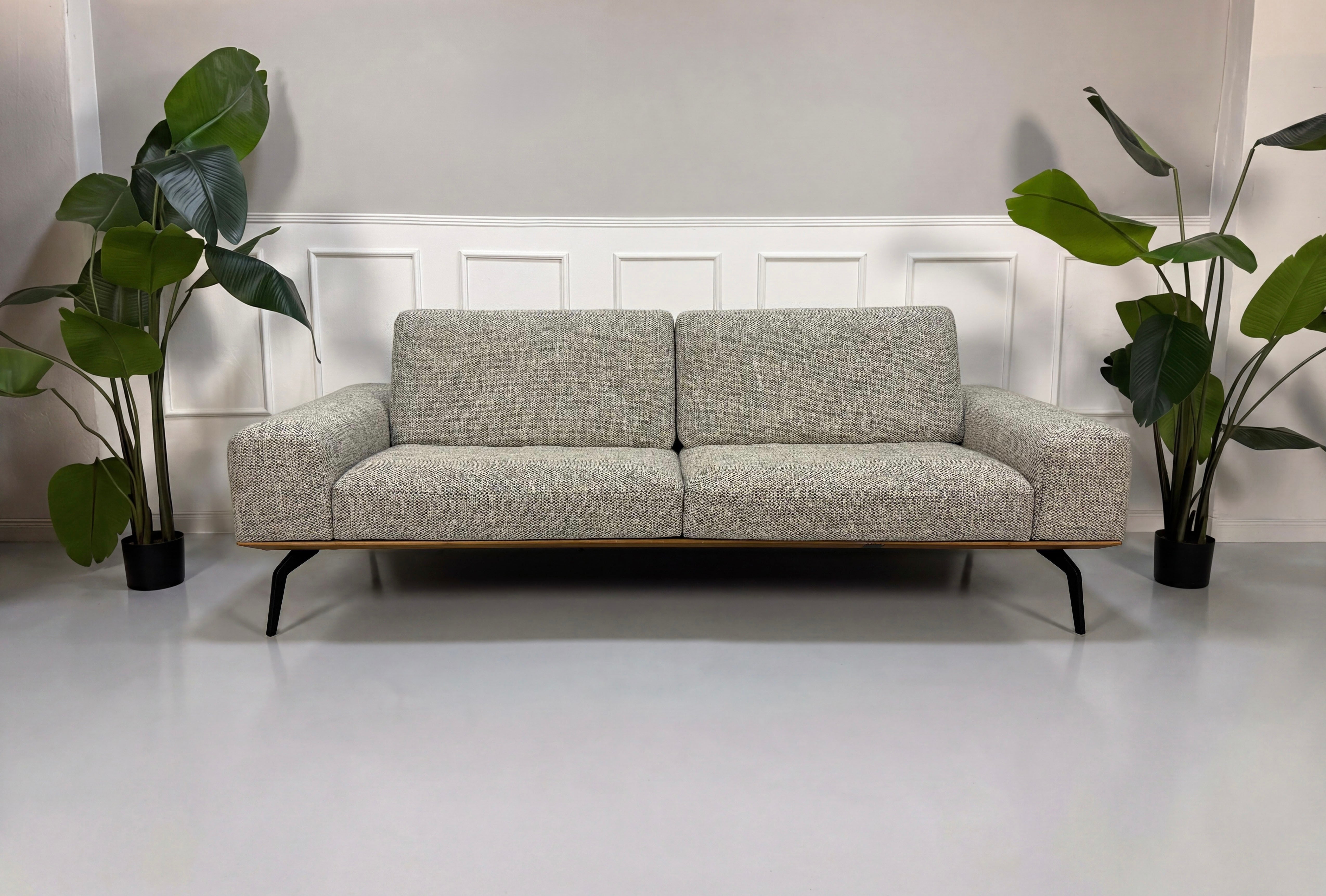 Gebrauchtes graues Koinor Hiero Designer Stoff Sofa vor einer Wand, stilvoll und modern eingerichtet.