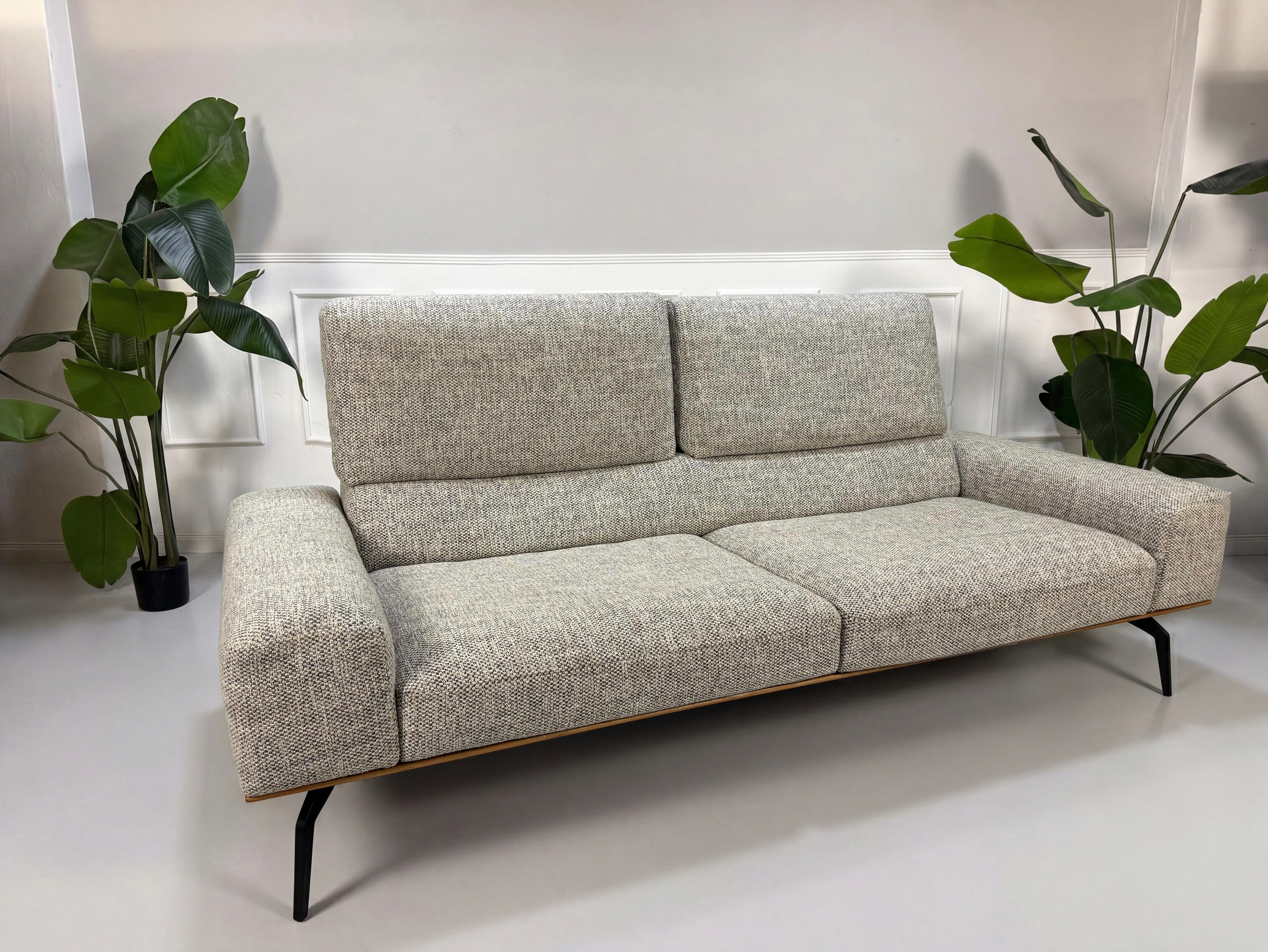 Gebrauchtes graues Koinor Hiero Designer Stoff Sofa vor einer Wand, stilvoll und modern eingerichtet.