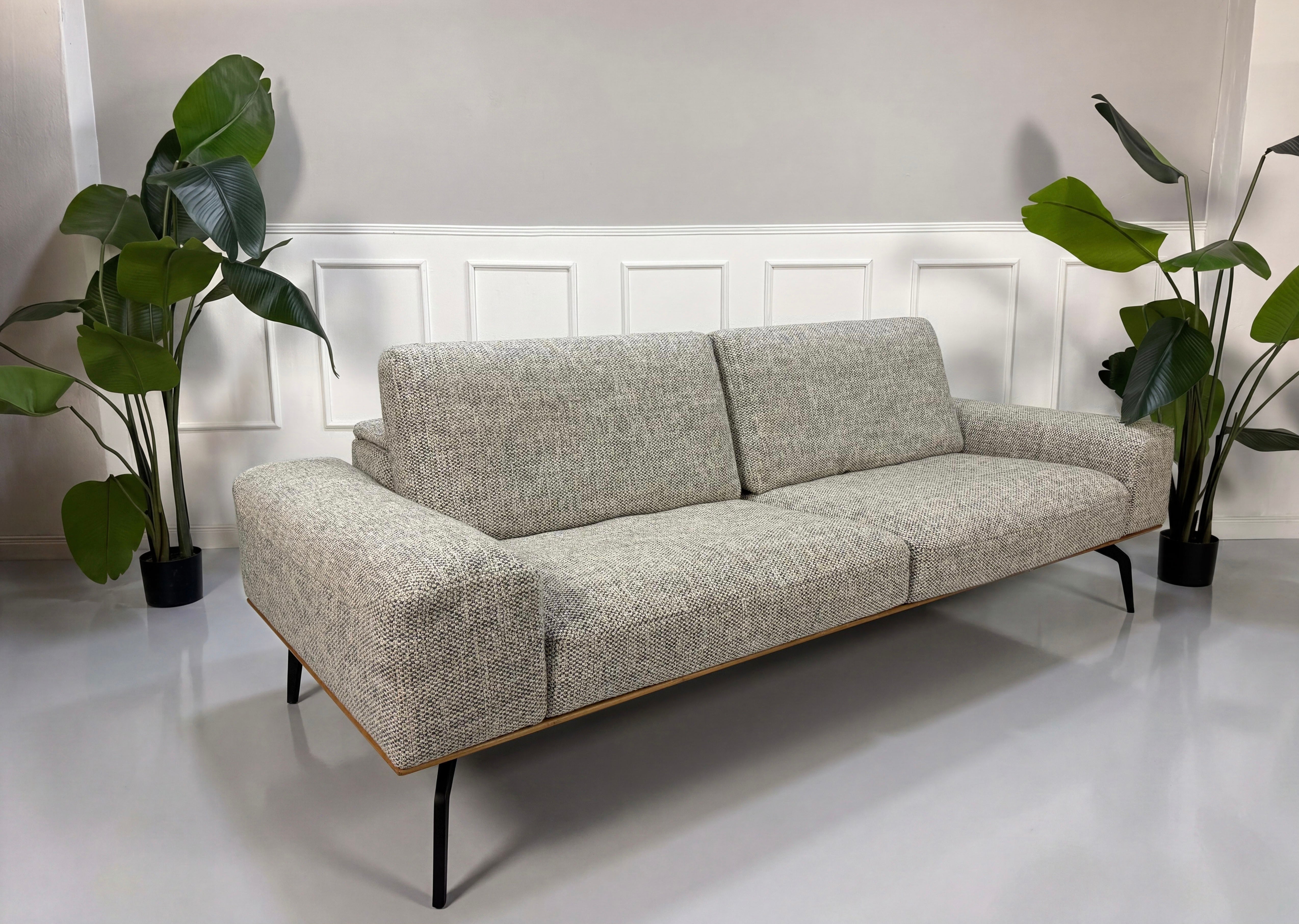Gebrauchtes graues Koinor Hiero Designer Stoff Sofa vor einer Wand, stilvoll und modern eingerichtet.