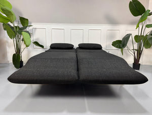 Gebrauchtes graues Rolf Benz Plura Designer Stoff Sofa mit Hocker vor einer Wand, stilvoll und modern eingerichtet.