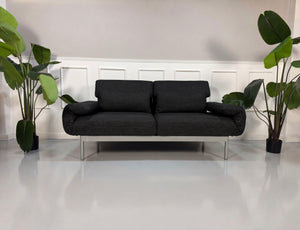 Gebrauchtes graues Rolf Benz Plura Designer Stoff Sofa mit Hocker vor einer Wand, stilvoll und modern eingerichtet.