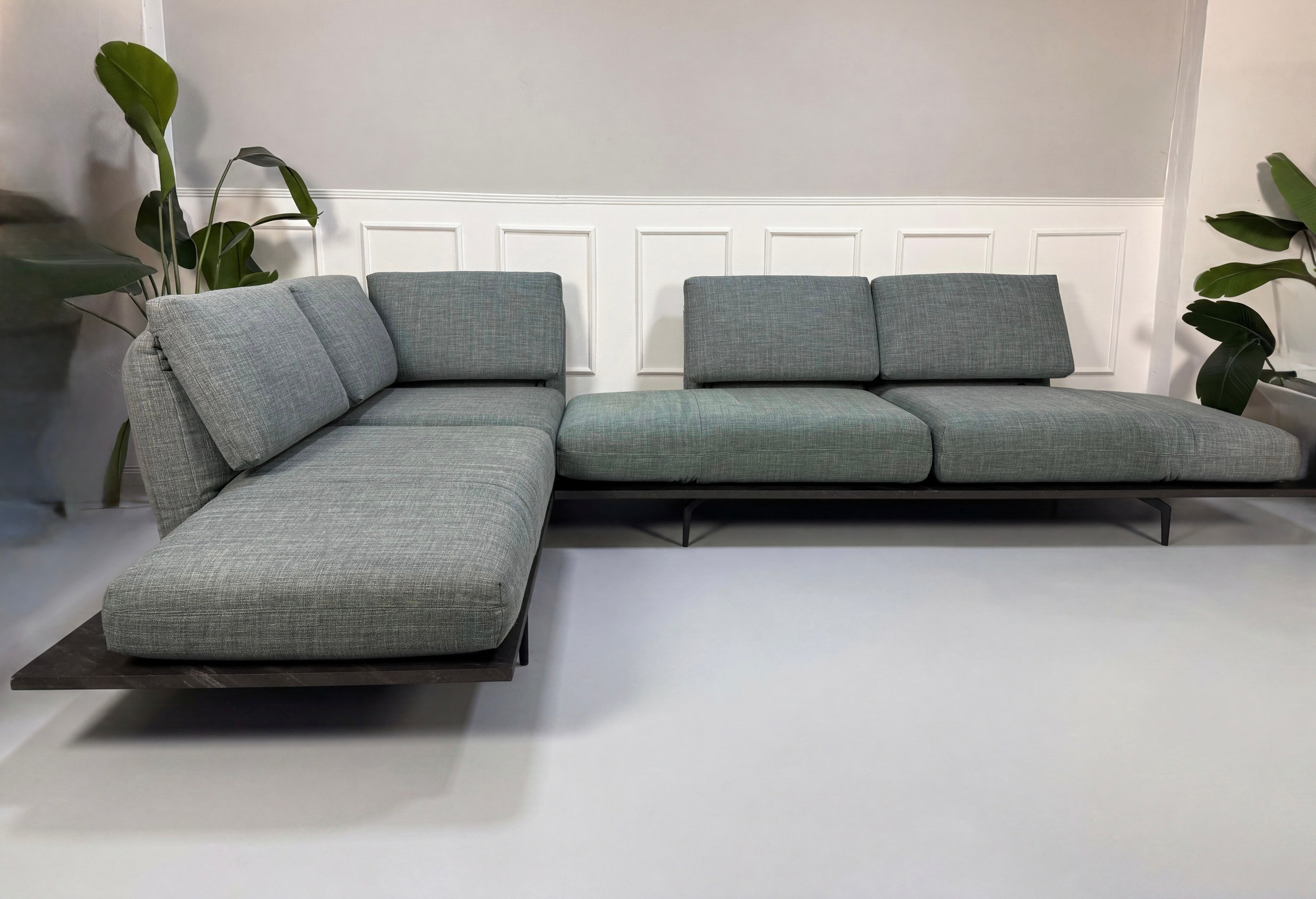Gebrauchtes blau graues Rolf Benz Aura Designer Stoff Sofa vor einer Wand, stilvoll und modern eingerichtet.

