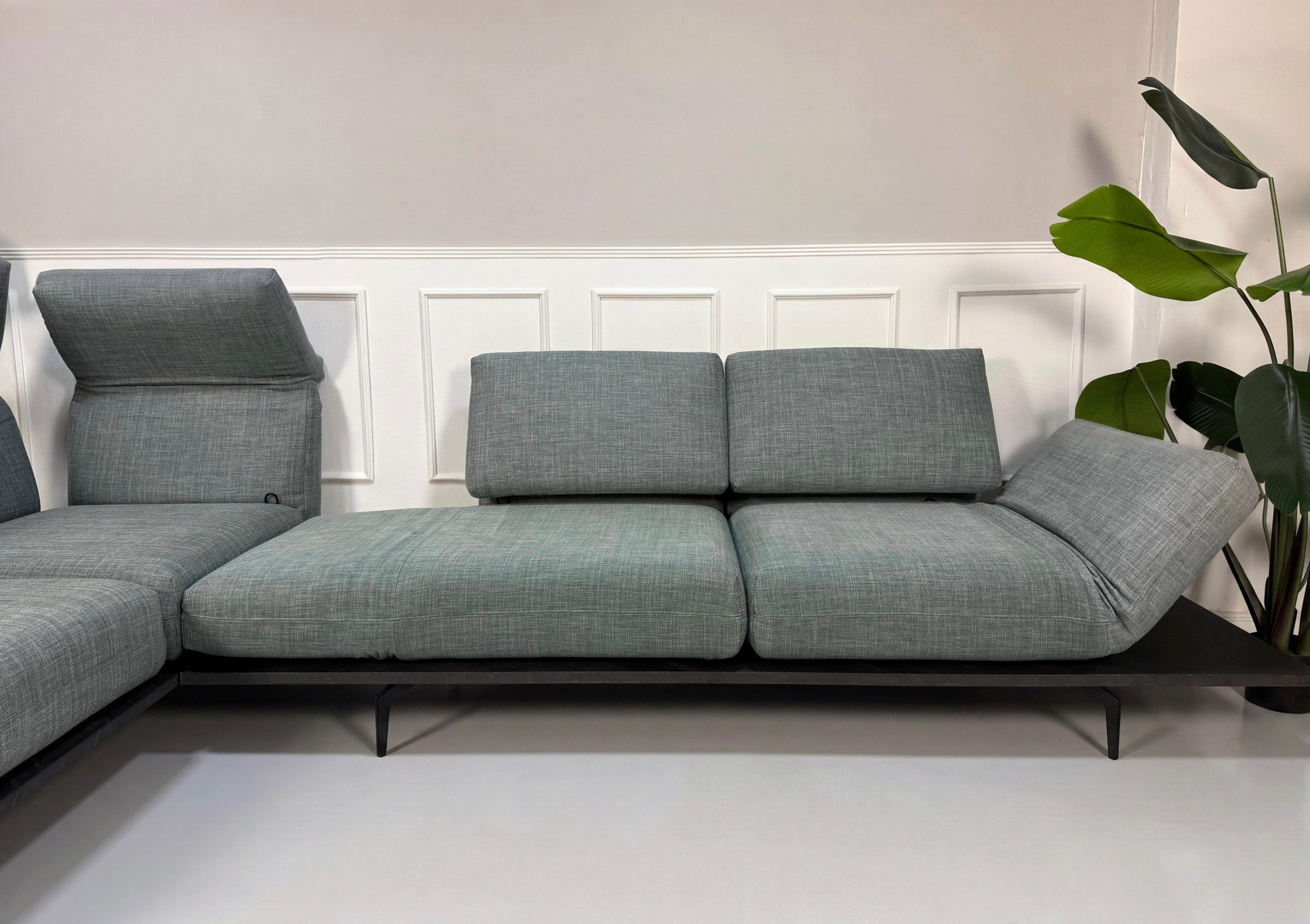 Gebrauchtes blau graues Rolf Benz Aura Designer Stoff Sofa vor einer Wand, stilvoll und modern eingerichtet.